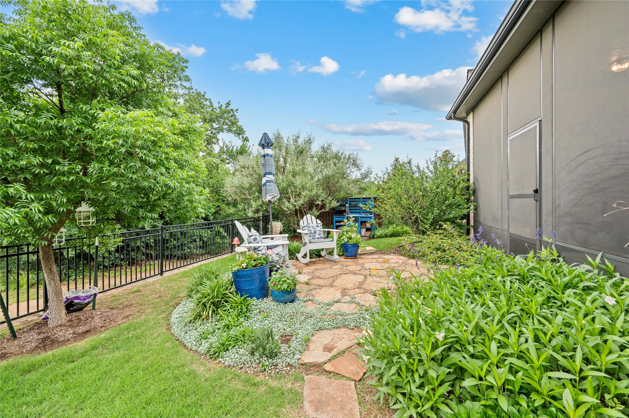 Rear exterior featuring a screened patio with a brick paver seating area, surrounded by diverse plantings, the natural side of wildridge and no neighbors!