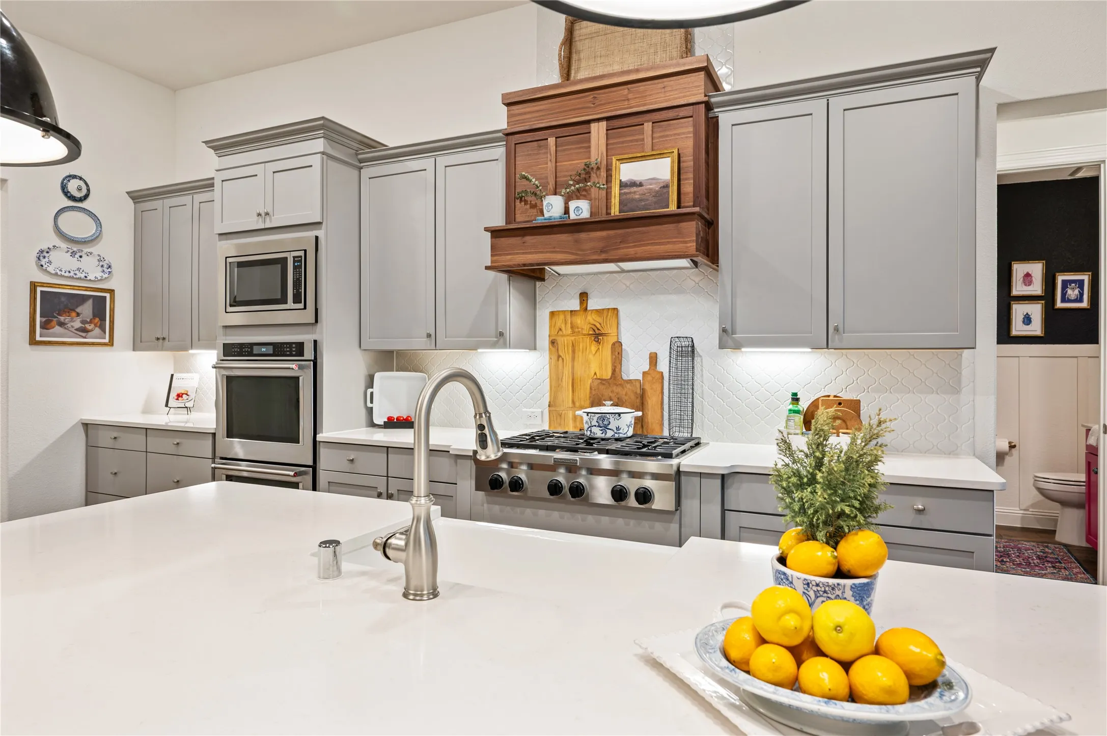 Gorgeous high end kitchen with large island, custom wood vent hood, modern painted cabinets, ss gas appliances, double oven, custom pendants and natural light throughout