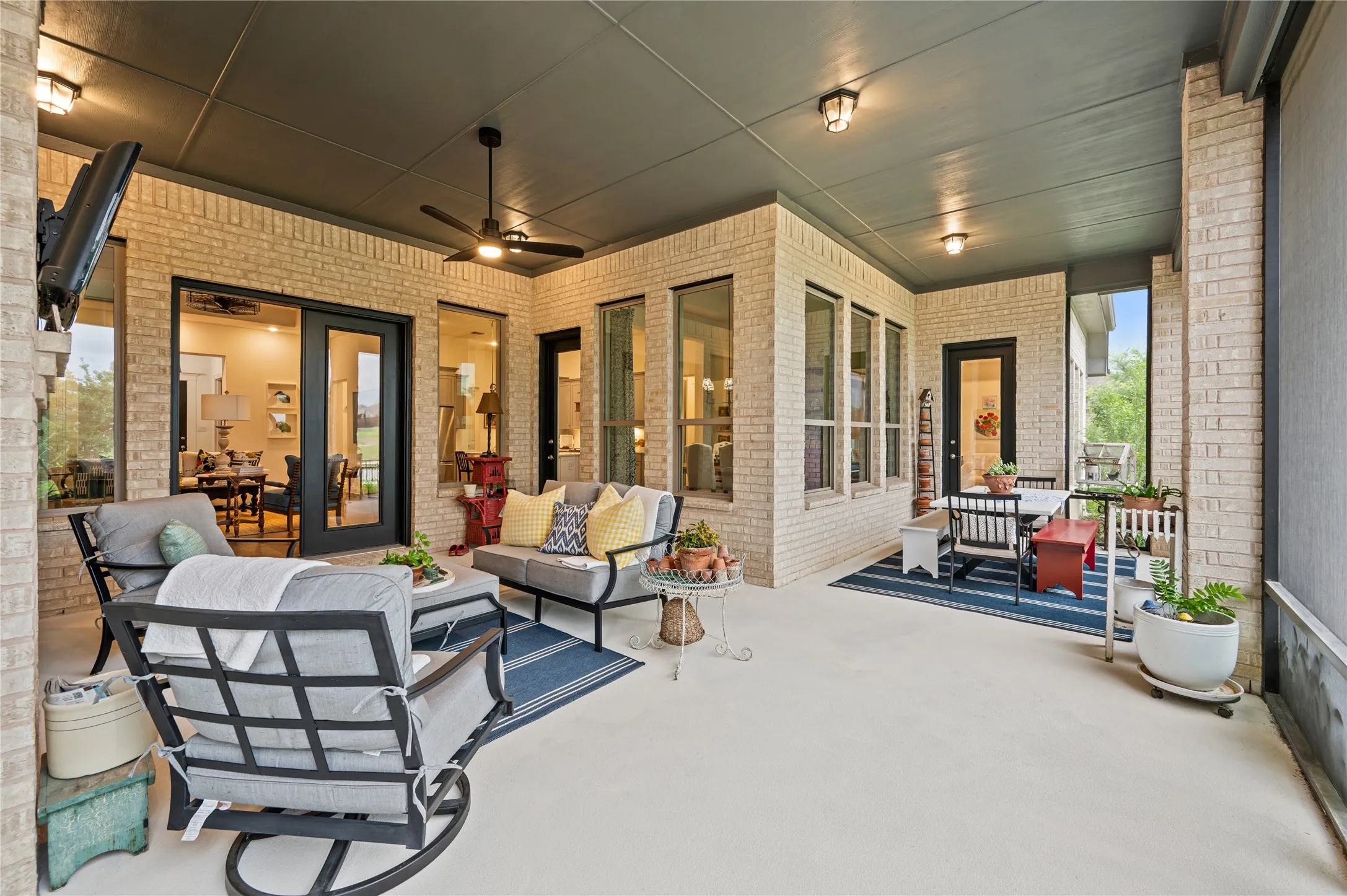 Expansive covered patio featuring a light brick exterior, concrete flooring, a dark ceiling with recessed lighting, and a ceiling fan