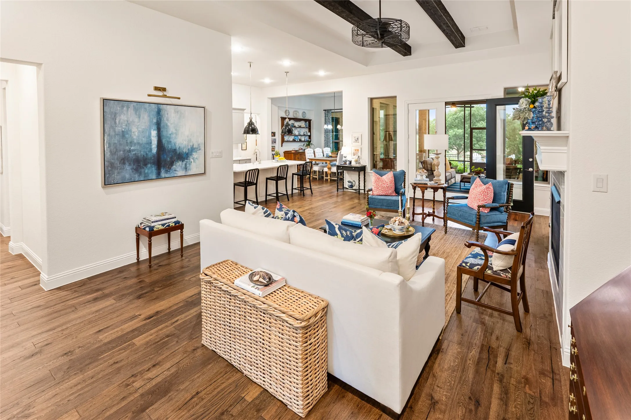 Spacious living area featuring wood flooring, a gas fireplace with a mantel, and exposed ceiling beams