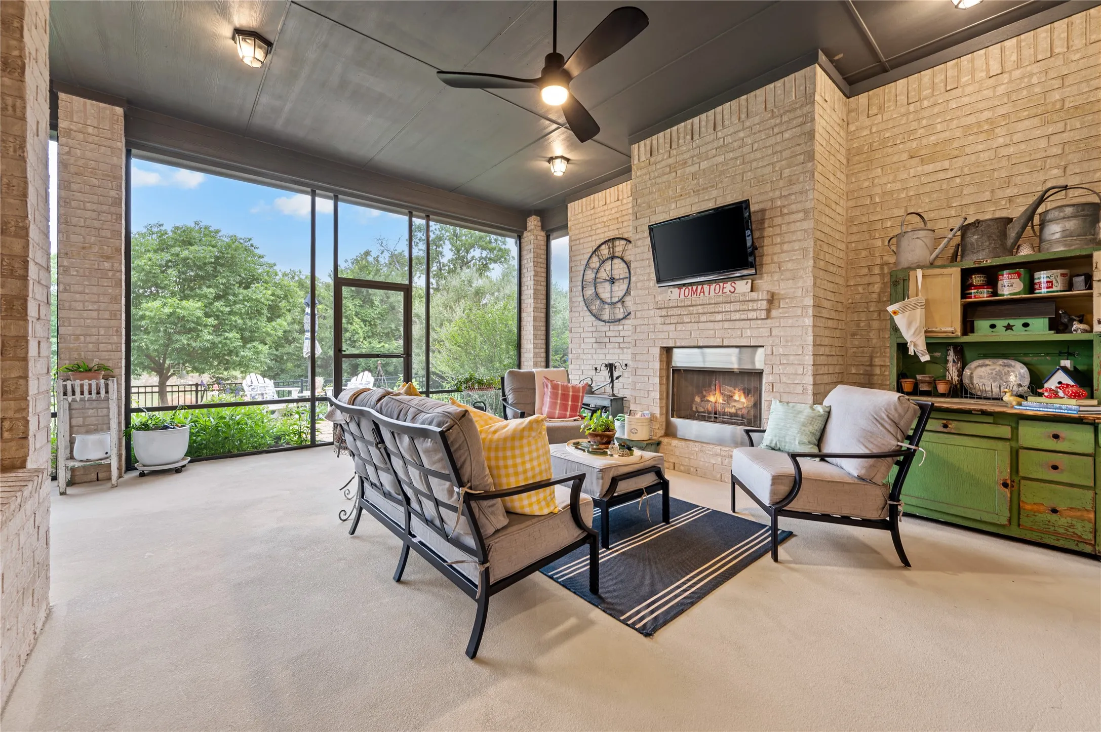 Screened outdoor living space featuring, an outdoor fireplace, large concrete extended space and a dark-toned ceiling with recessed lighting, ceiling fan, and gas stub for outdoor grill