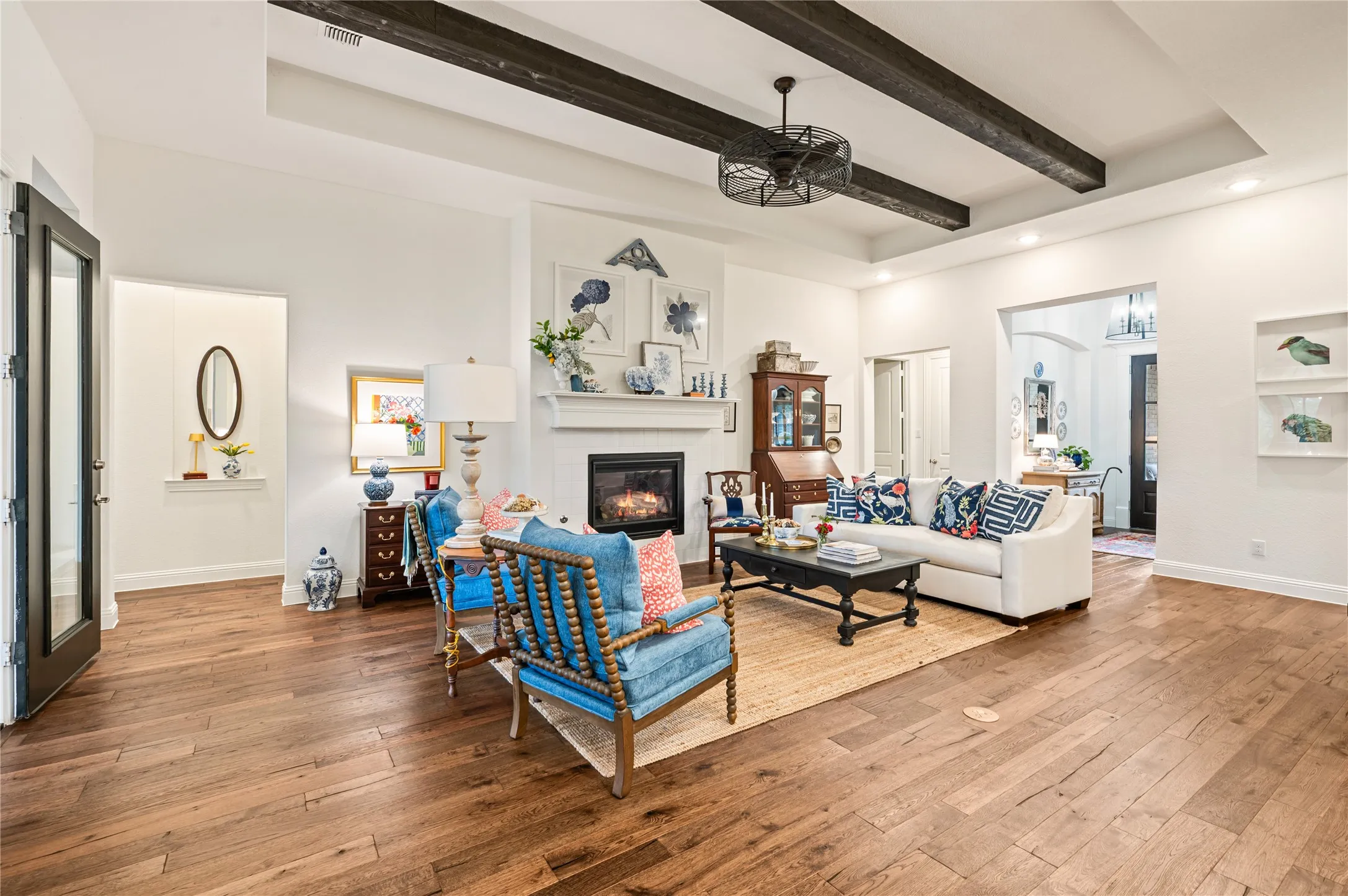Open-concept living space featuring wood flooring, exposed ceiling beams, recessed lighting, and a modern ceiling fan with views of kitchen and dining space