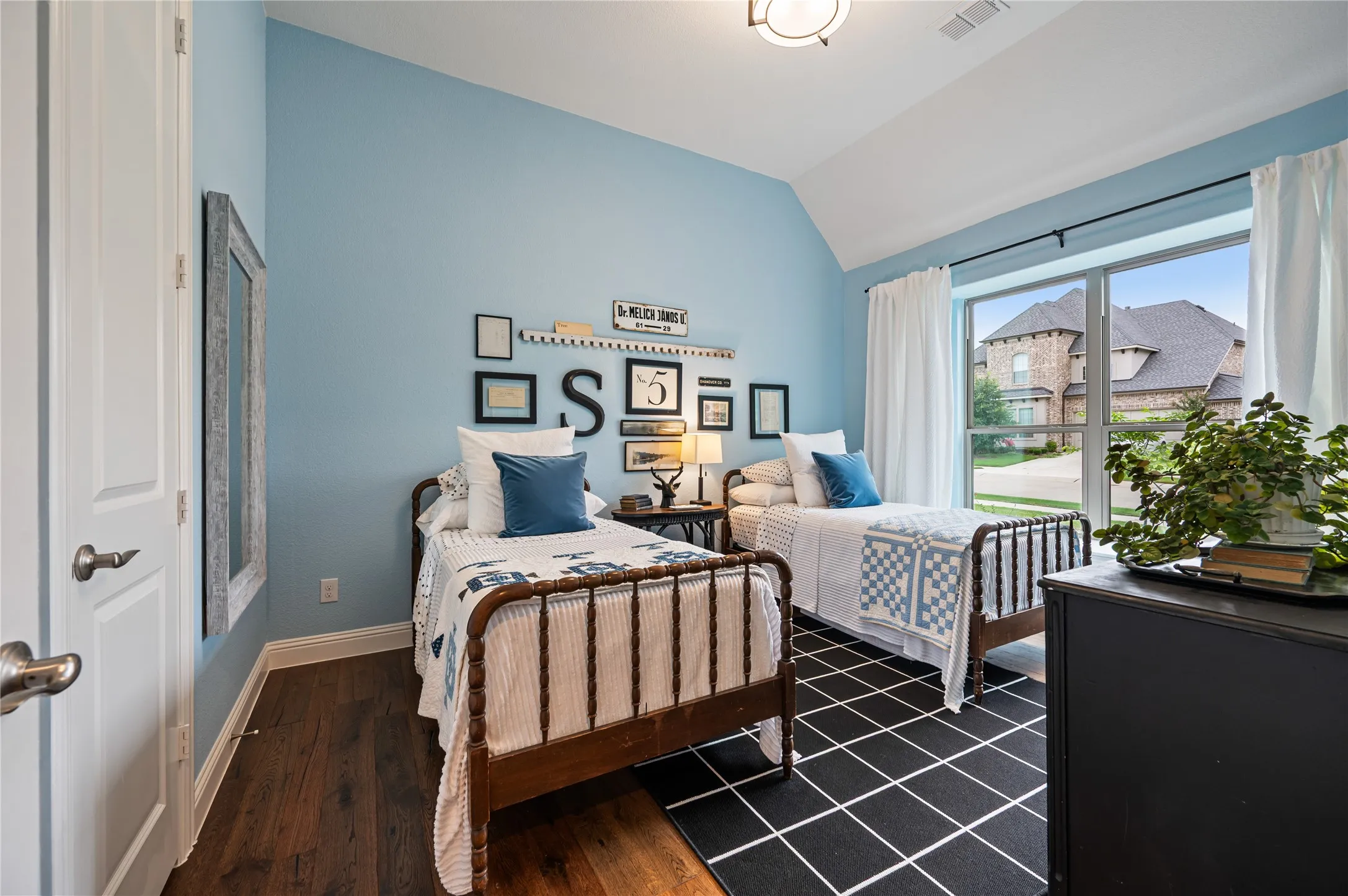 Bedroom featuring a vaulted ceiling, wood-flooring, and a large window with walk in closet