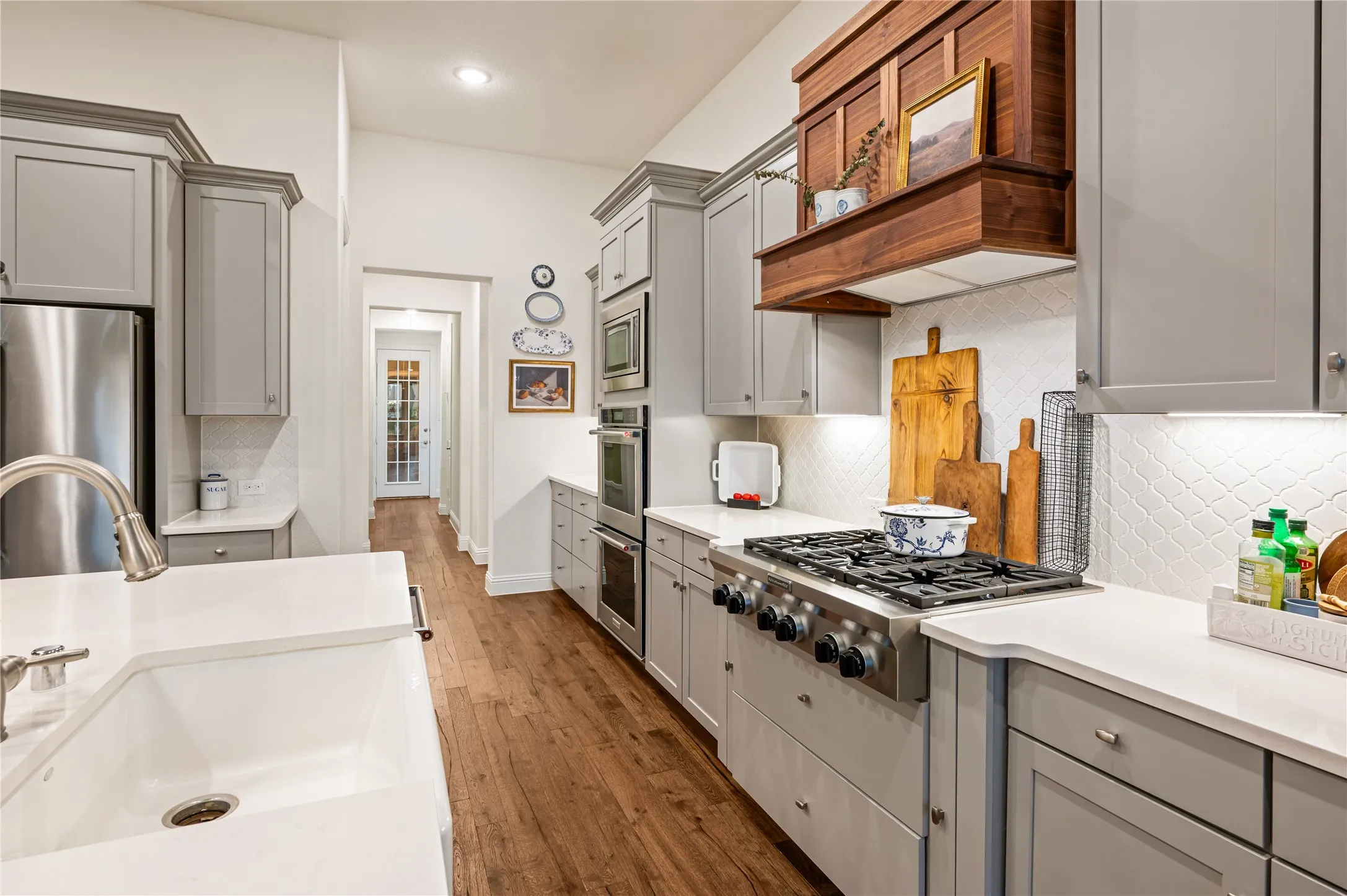 Galley kitchen with wood-finish flooring, white countertops, and light gray cabinetry