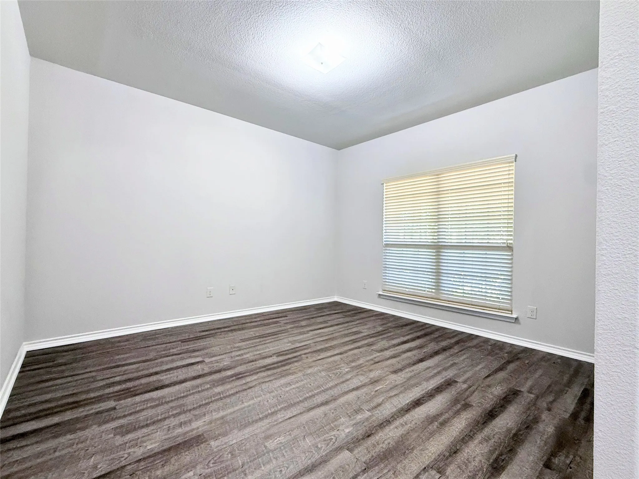 Room featuring wood-finish flooring, neutral wall paint, and white baseboards