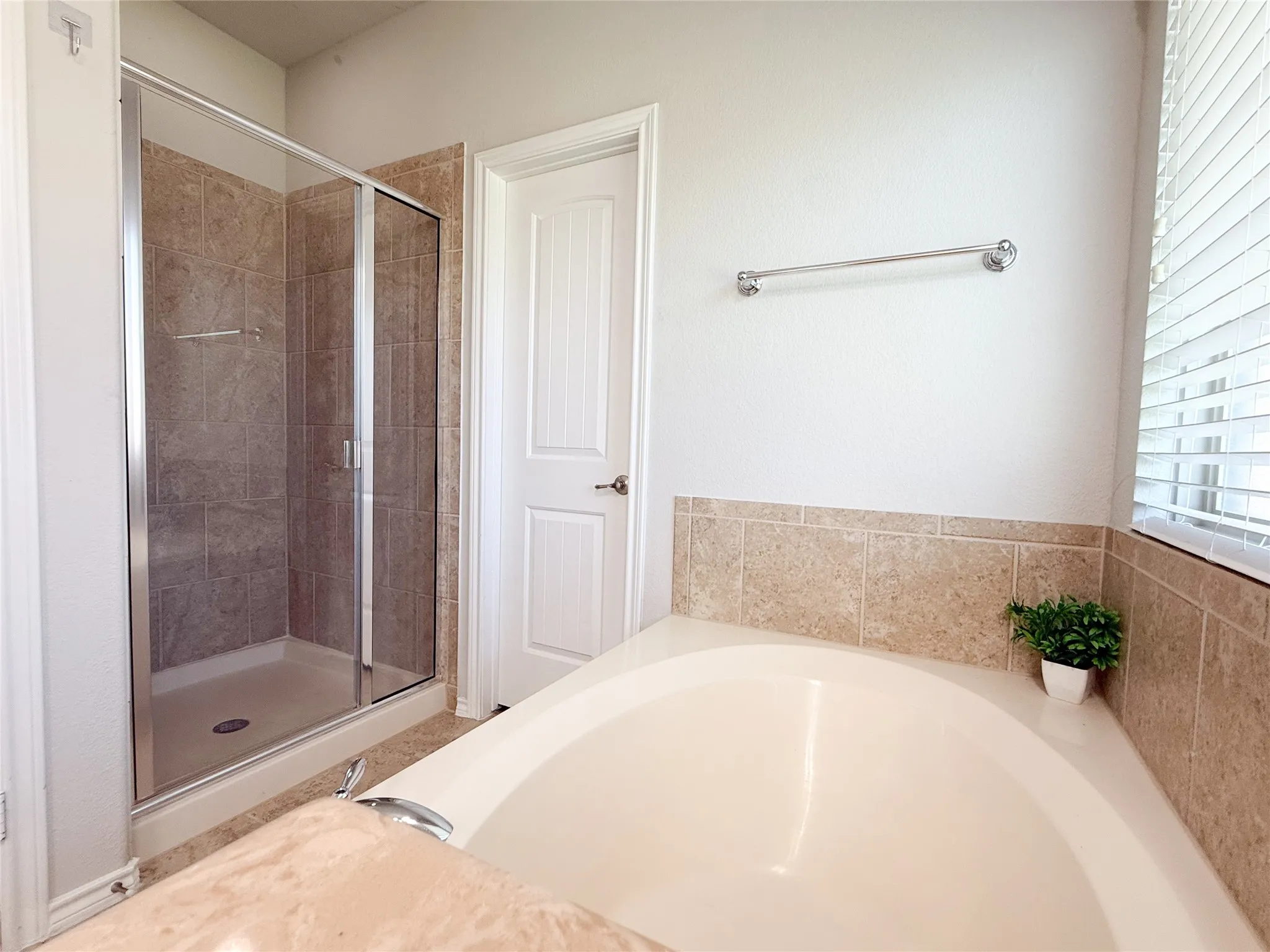 Bathroom featuring a built-in tub, tiled surround, and a separate glass-enclosed shower with tiled walls