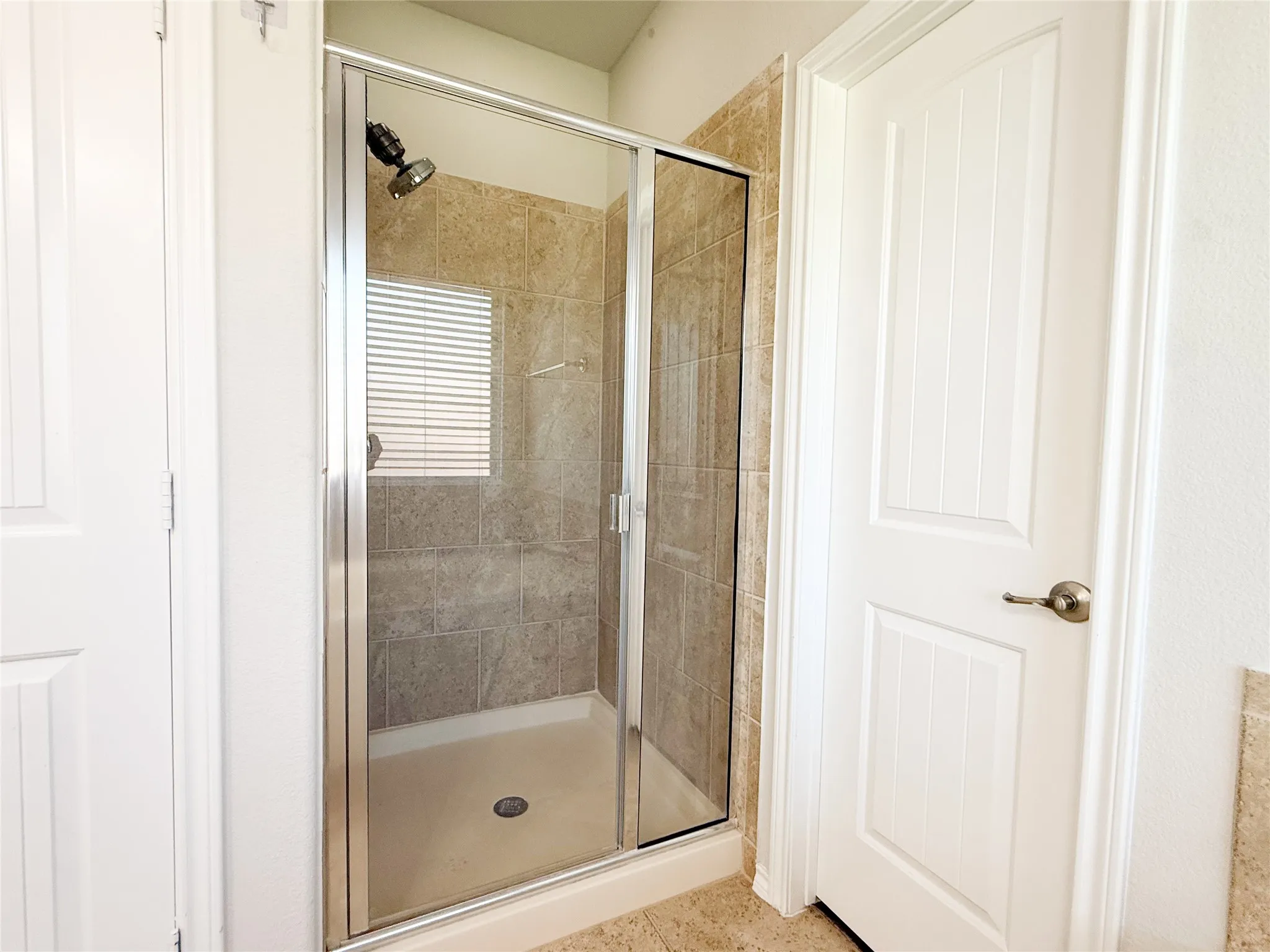 Enclosed shower with clear glass door and brushed metal frame