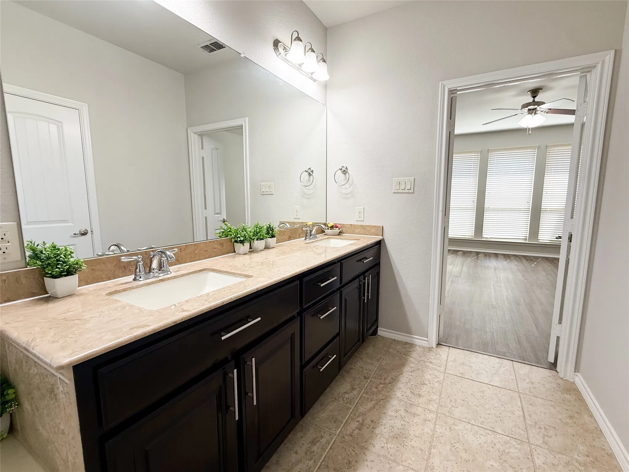 Dual vanity with light-toned countertop, integrated sinks, and dark cabinetry