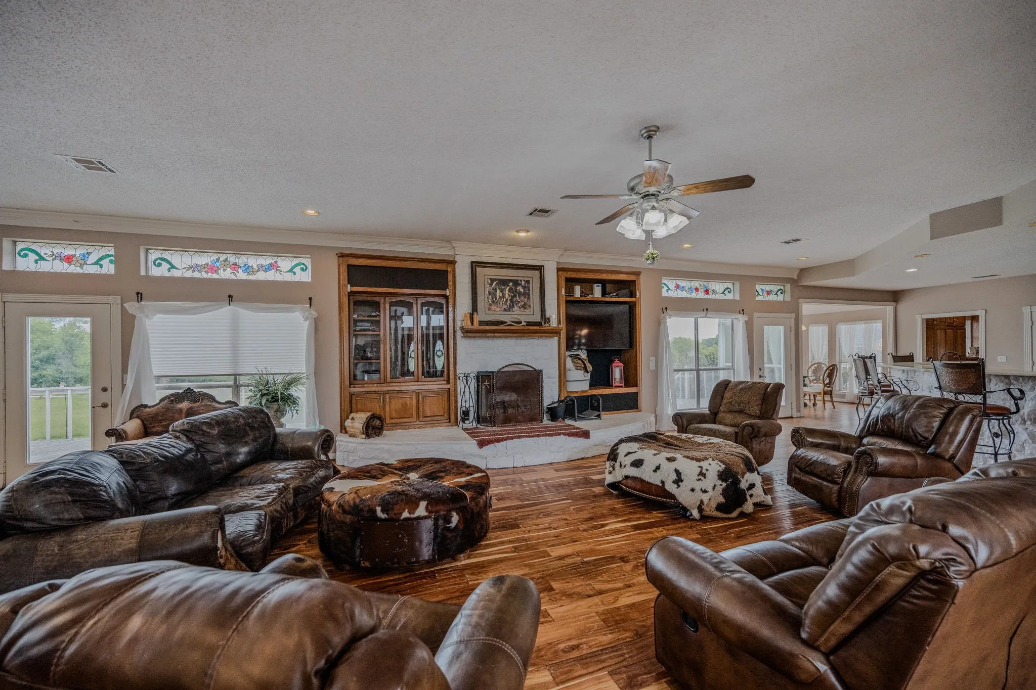 Spacious living area featuring wood-finish flooring, a white brick fireplace with a wood mantle, and built-in shelving