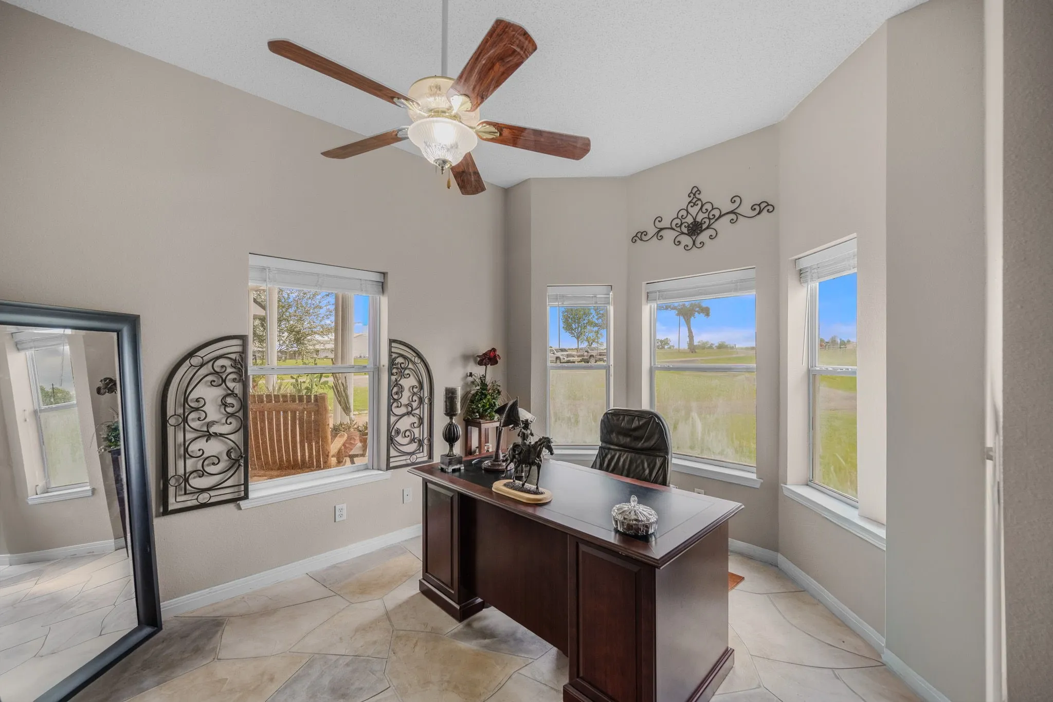 Bay window area featuring flagstone flooring, a ceiling fan with light fixture, and multiple windows overlooking exterior scenery