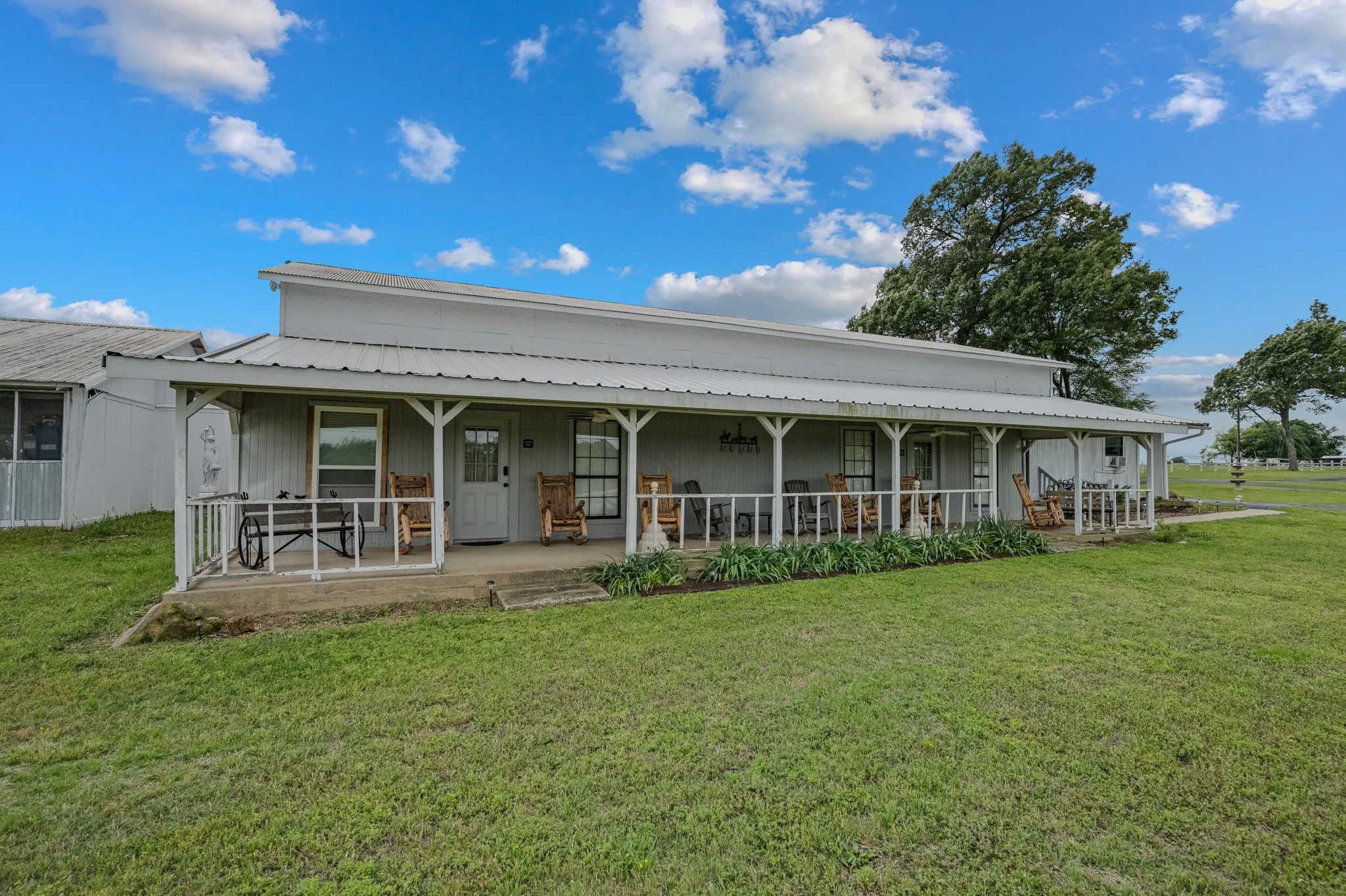 Ranch-style exterior with a full-length covered porch, white metal roof, and white painted siding