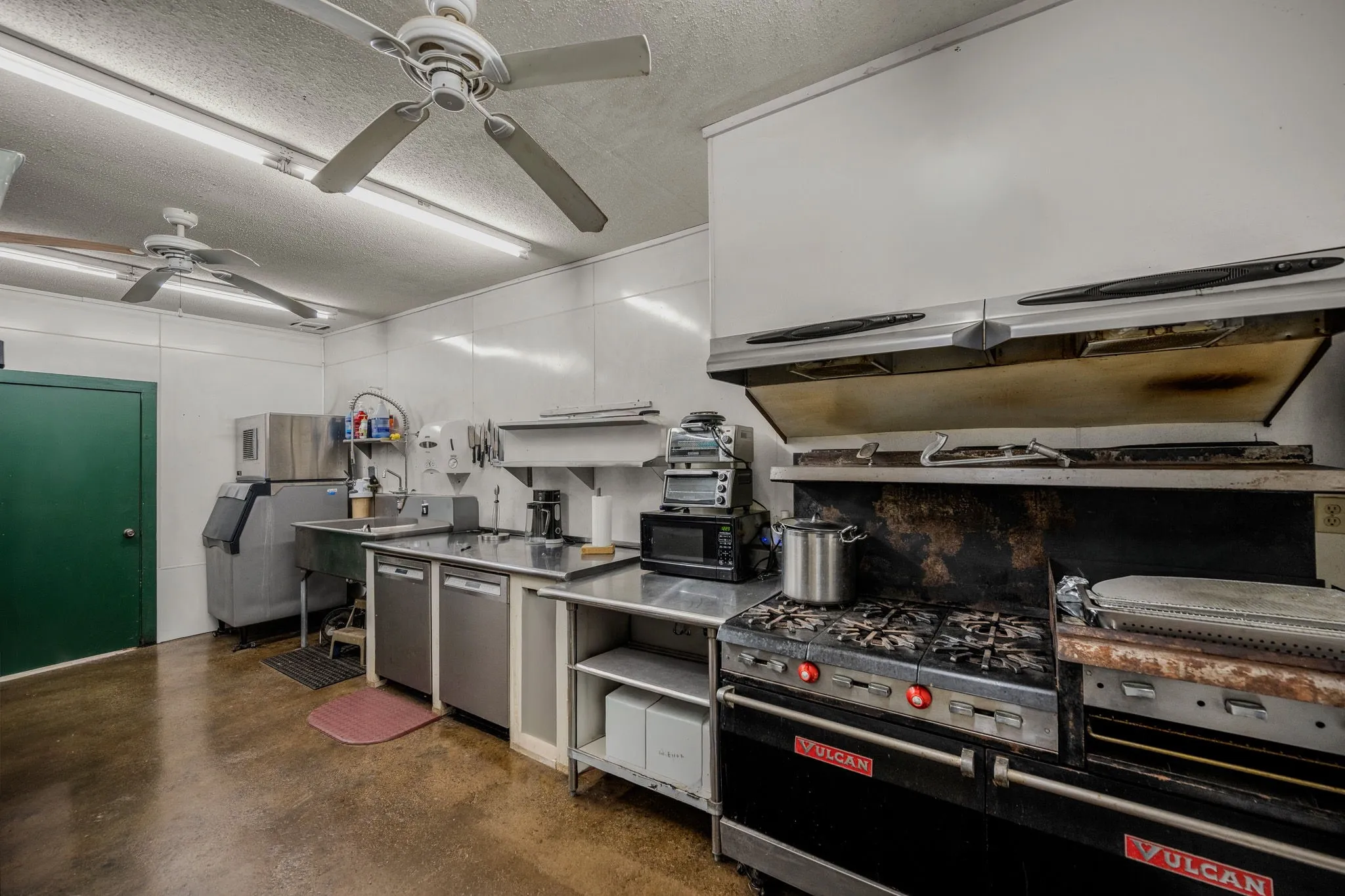 Commercial-grade kitchen space featuring a large gas range with griddle, stainless steel countertops, and a double basin sink