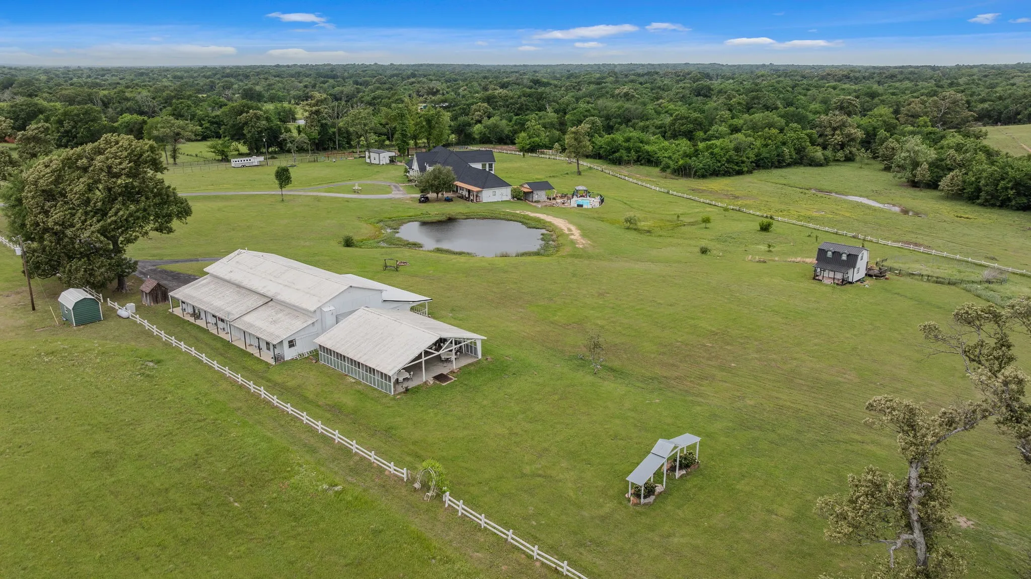 Expansive rural acreage featuring multiple structures, a private pond, and perimeter fencing