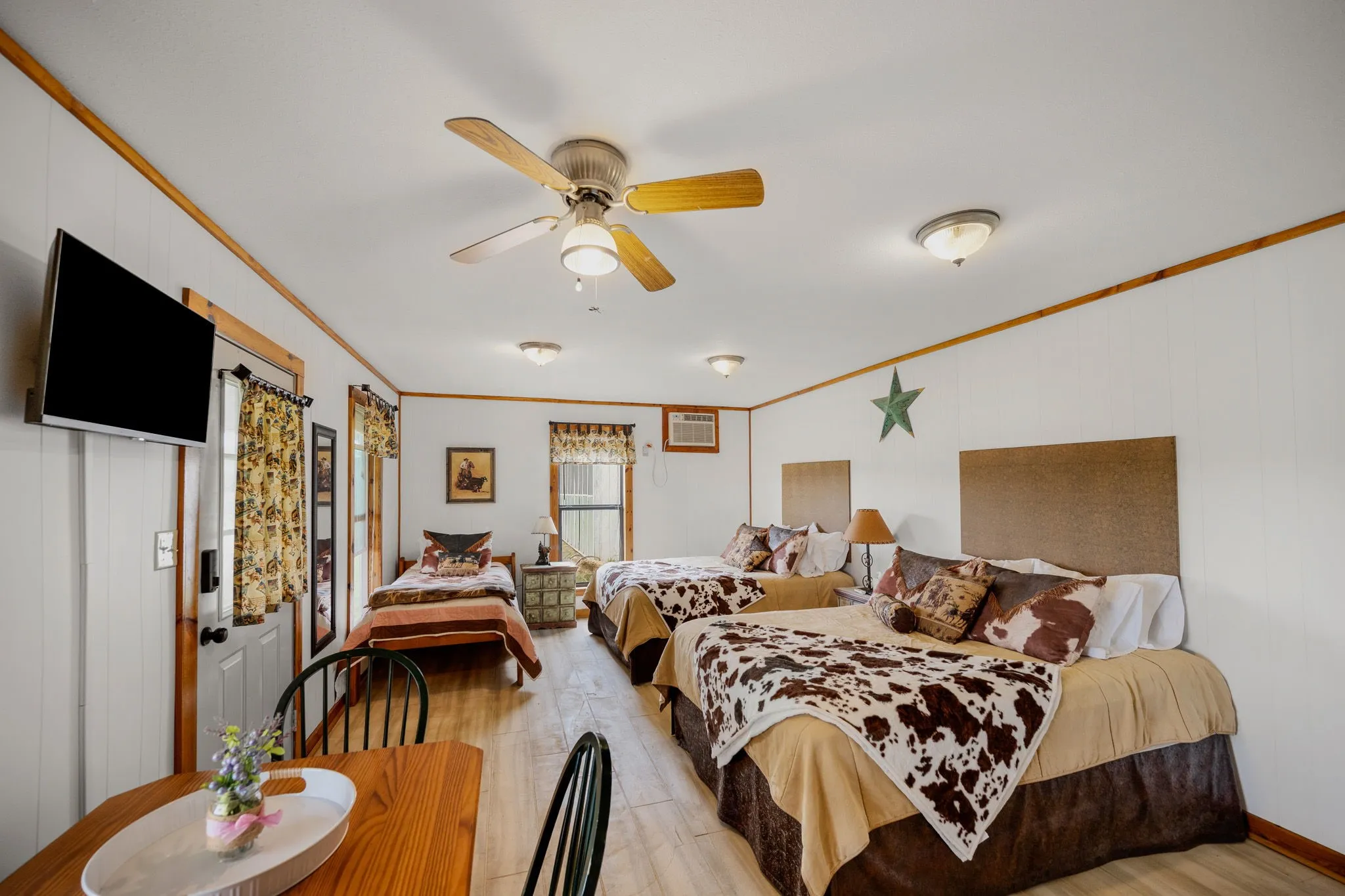 Spacious room with wood-finish flooring, white paneled walls, and wood trim accents