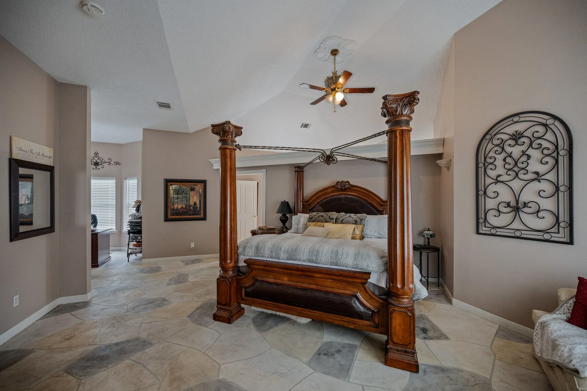 Spacious room featuring flagstone-style flooring, vaulted ceilings, and a ceiling fan with integrated lighting