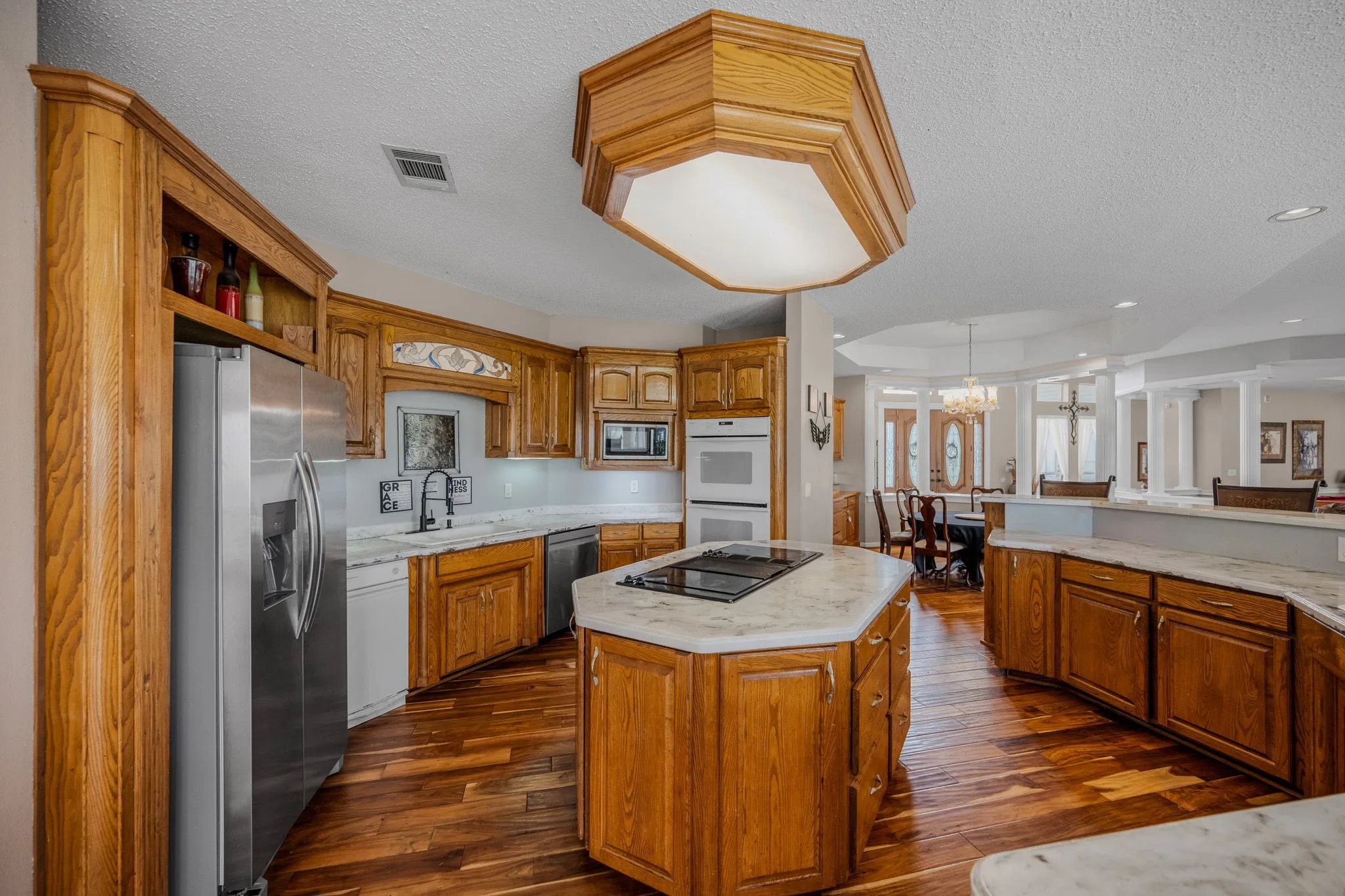 Kitchen featuring wood-finish flooring, custom wood cabinetry, and stone countertops
