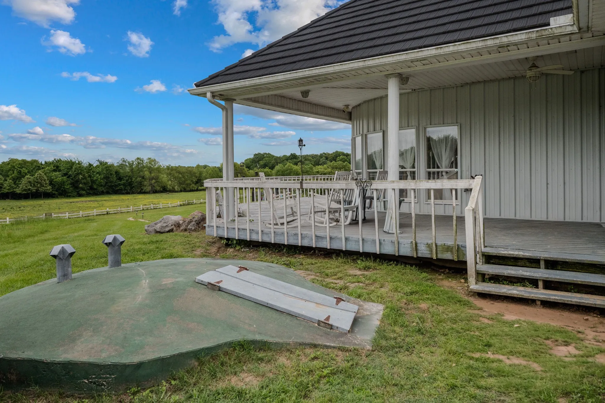 Exterior porch with white railing, featuring multiple windows and a gray metal roof