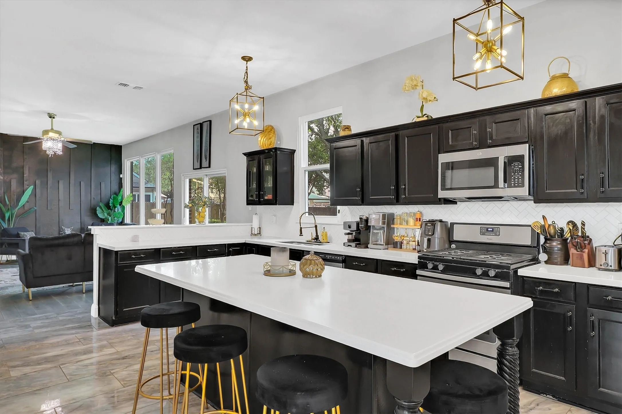 Kitchen featuring a center island with seating, dark cabinetry, white countertops, stainless steel appliances, and a herringbone tile backsplash