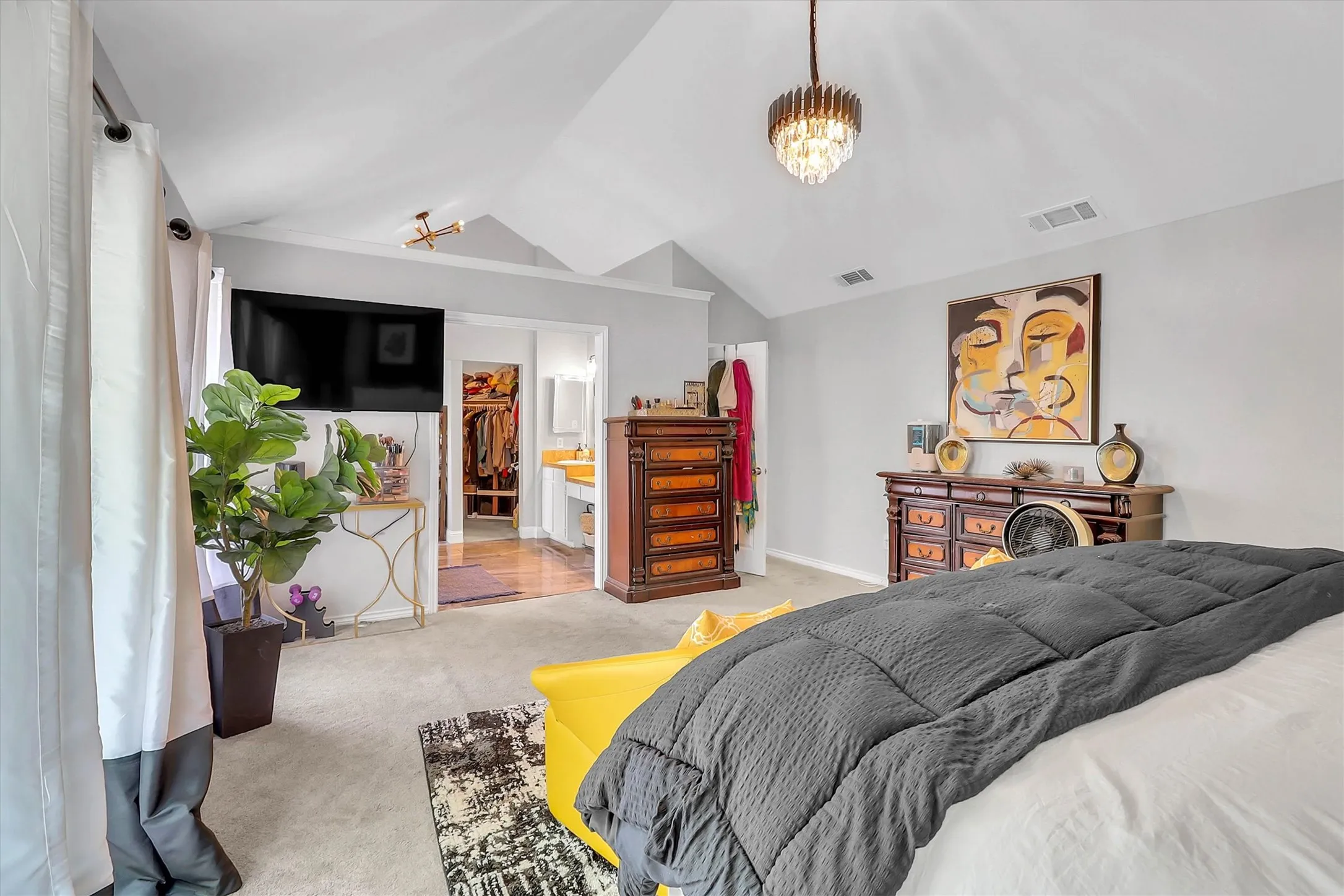 Vaulted ceiling room featuring carpet flooring, contemporary lighting fixtures, and direct access to a separate dressing area with a built-in closet system