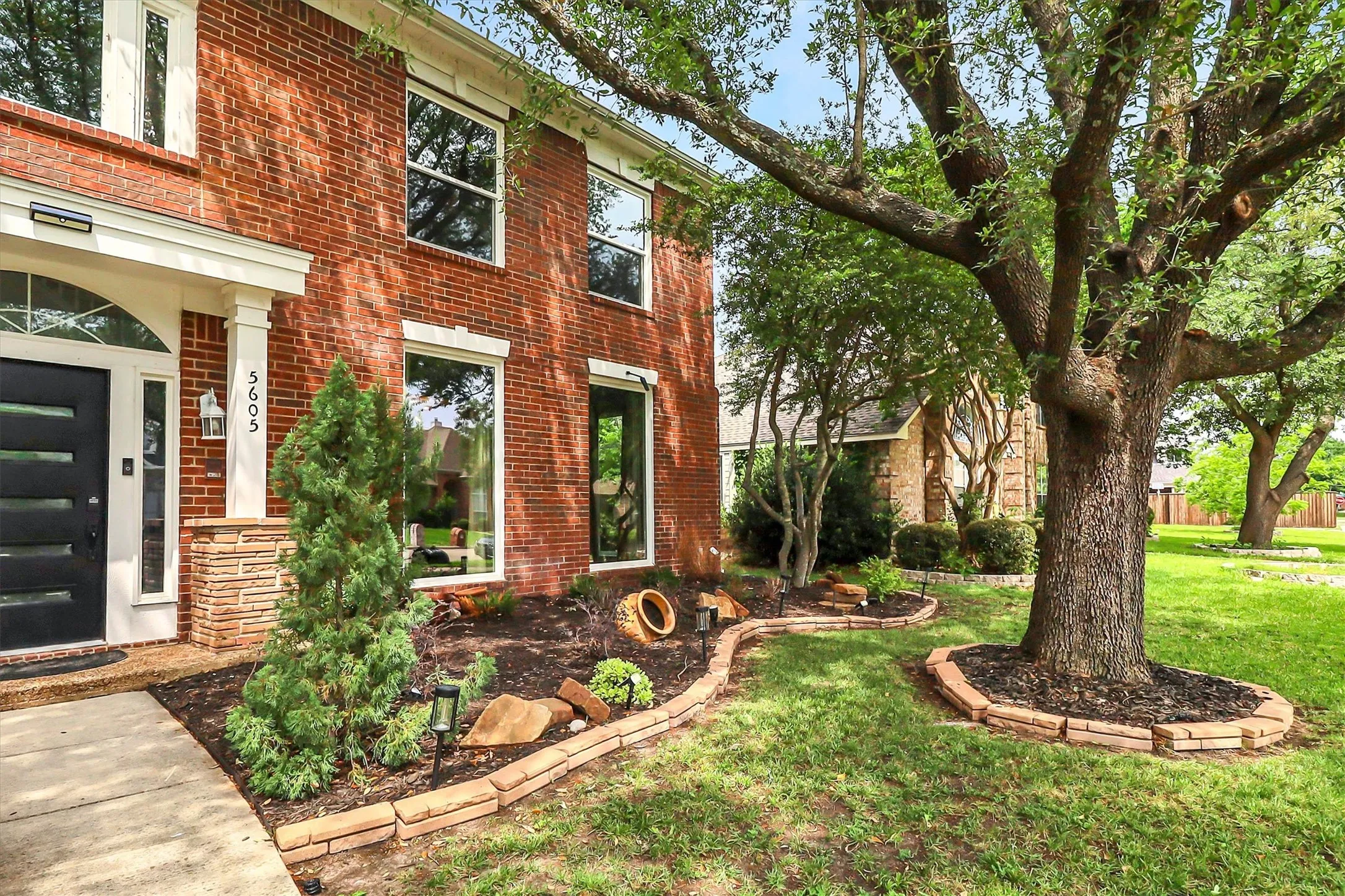 Brick facade home with multiple windows, featuring a prominent front entrance with a dark, segmented door and sidelights