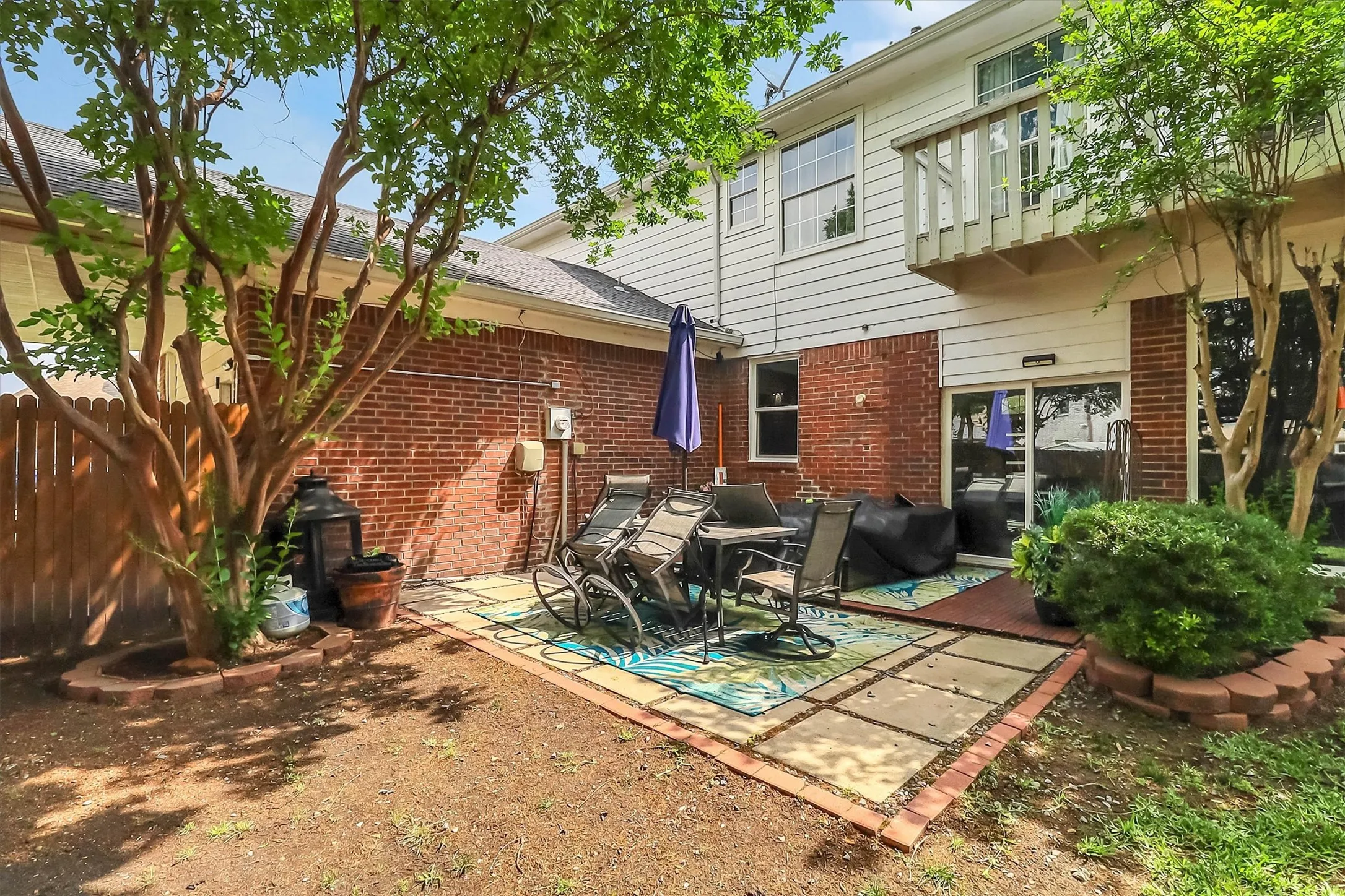 Multi-level patio area featuring concrete pavers, brick trim, and a sliding glass door