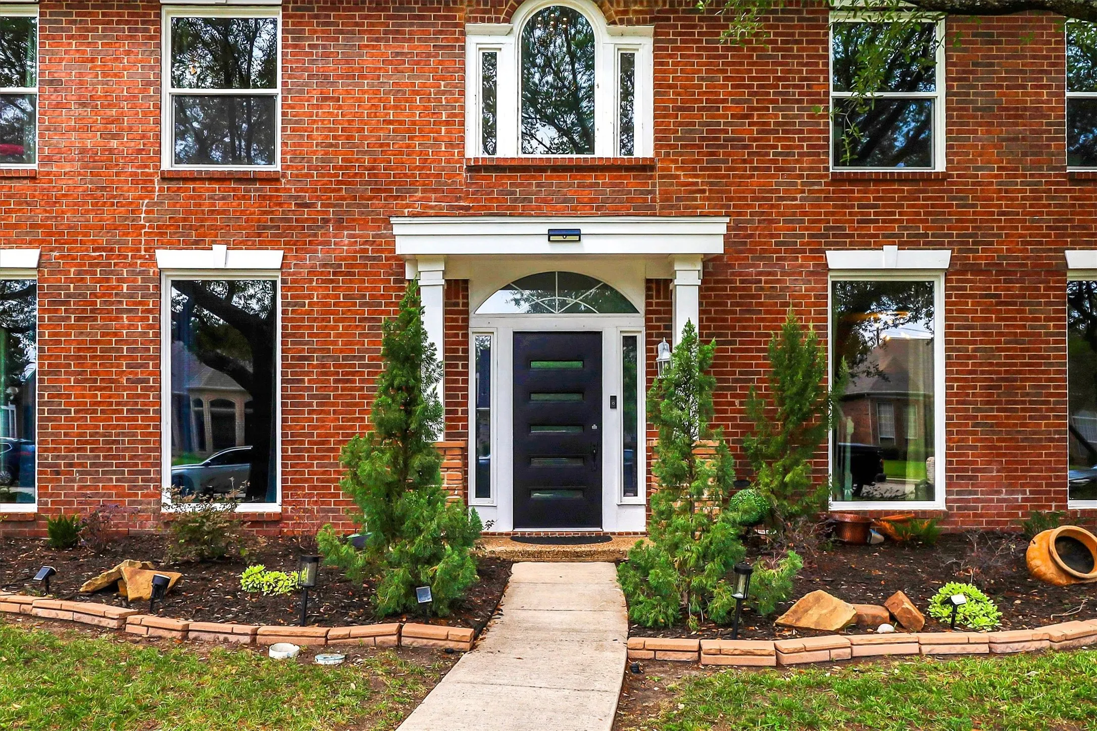 Red brick exterior featuring a recessed entry with white columns and an arched transom window