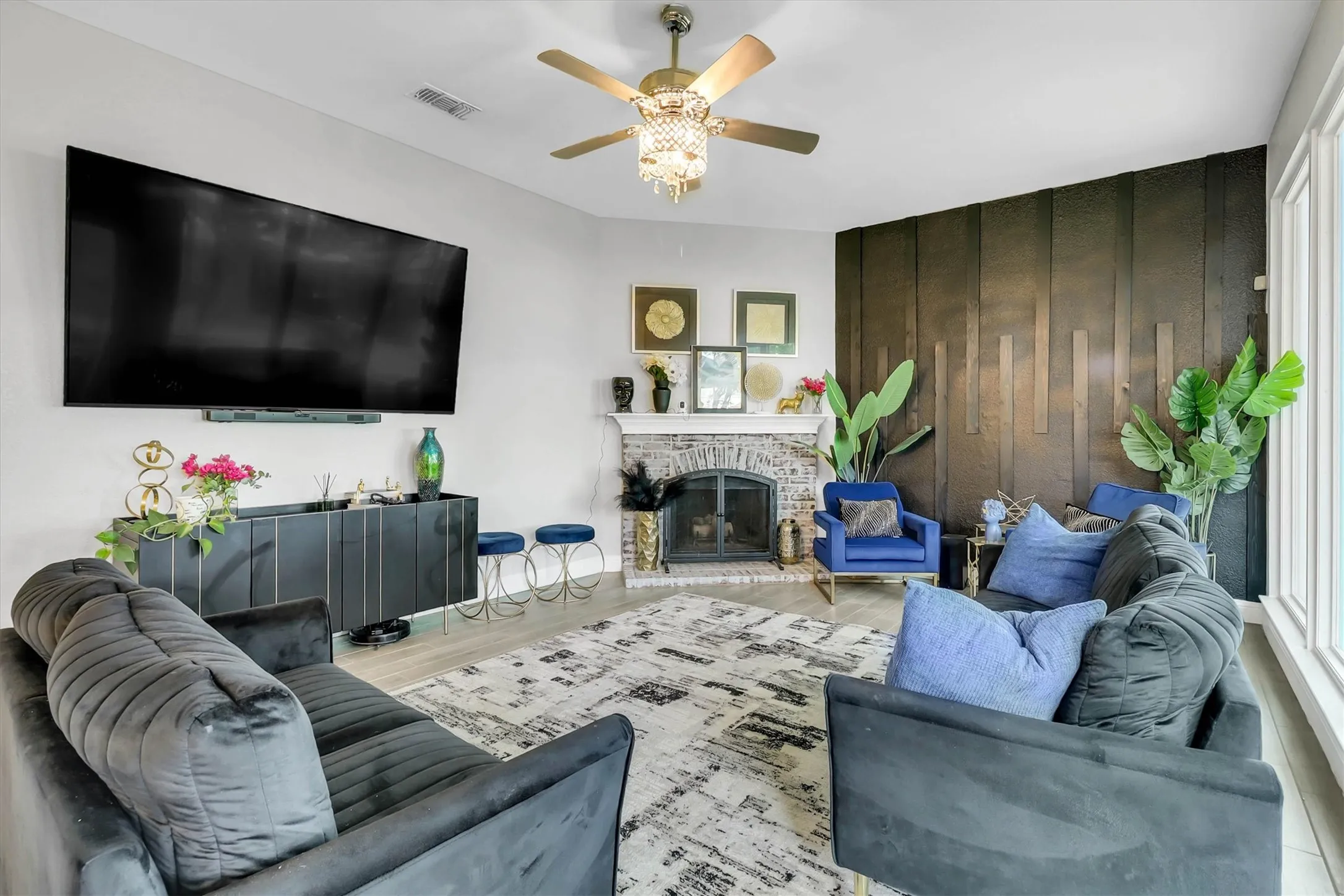 Spacious living area featuring light wood-finish flooring and a ceiling fan with integrated lighting