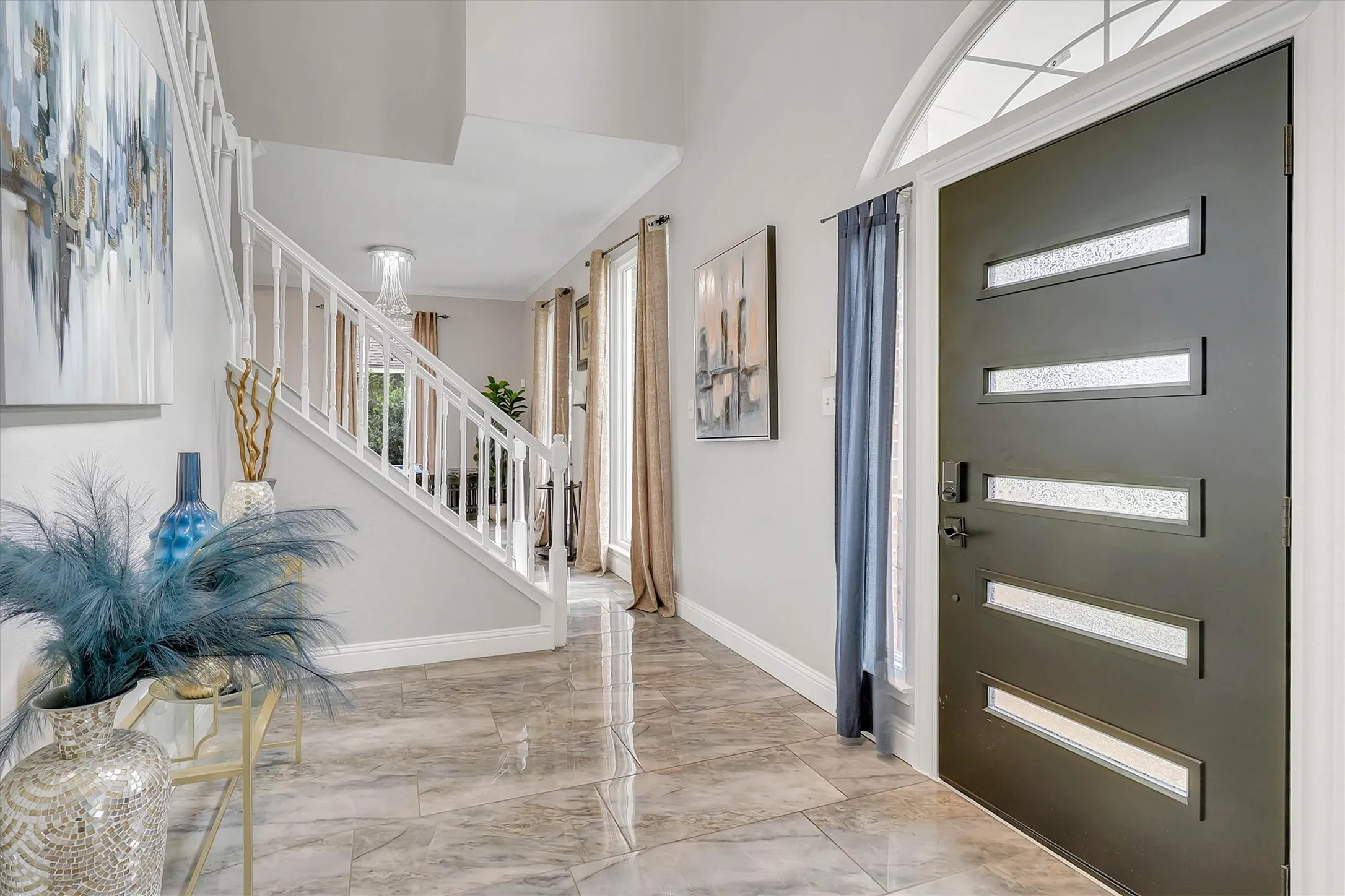 Entryway featuring a contemporary dark-finish door with frosted glass inserts, a semicircular transom window, and large format tile flooring