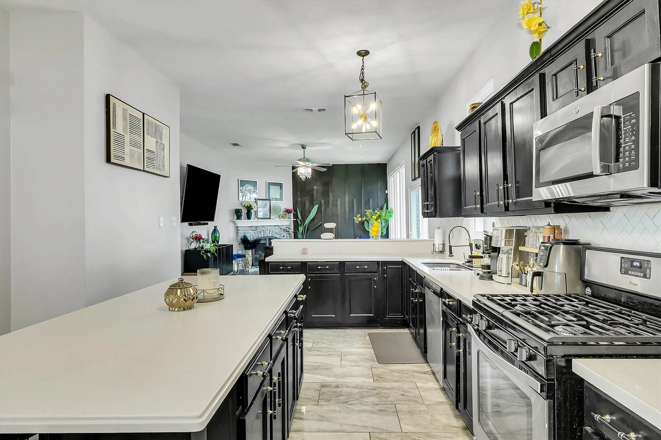 Kitchen featuring dark cabinetry, white countertops, stainless steel appliances, a white herringbone tile backsplash, and light-toned tile flooring