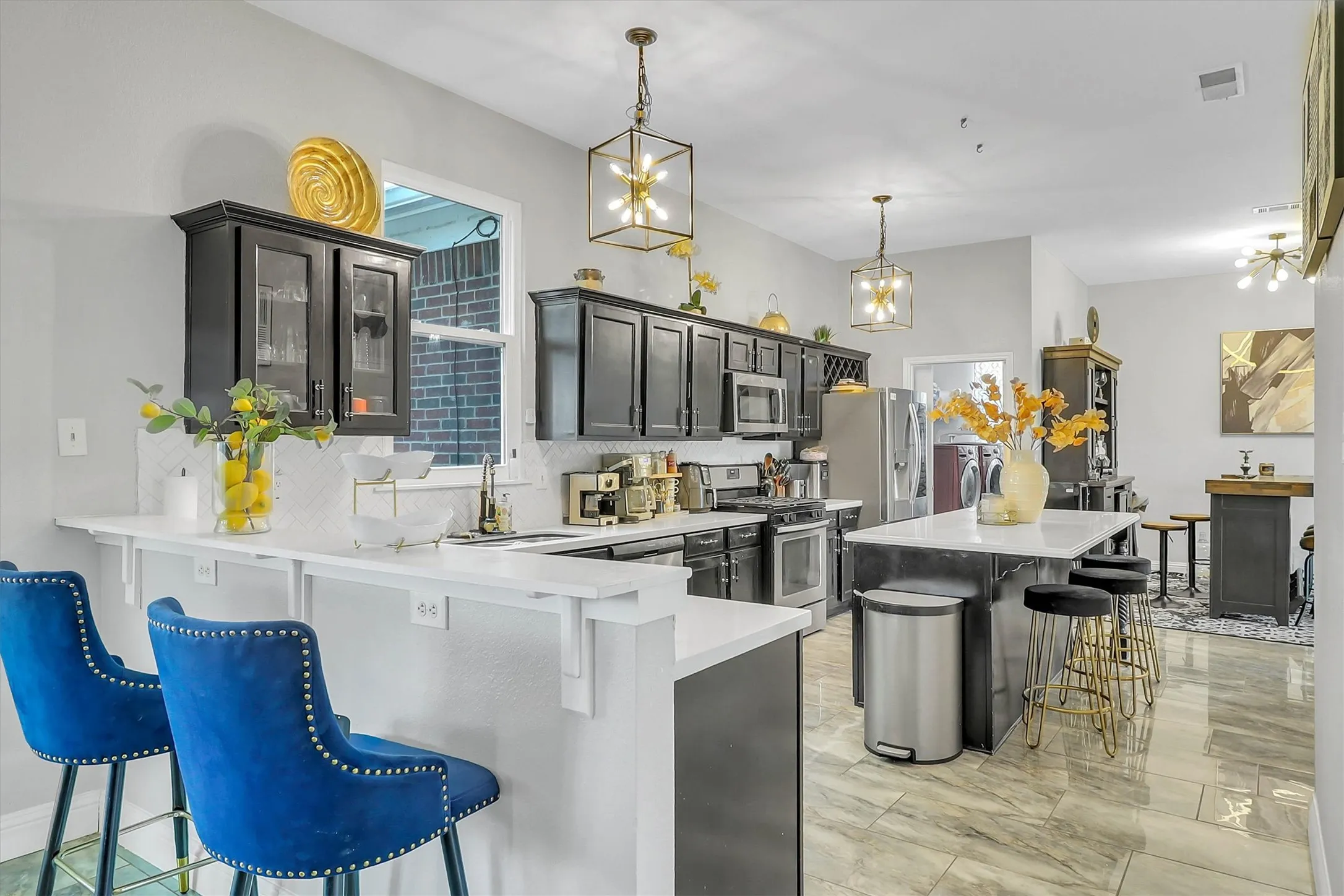 Spacious kitchen featuring dark cabinetry, stainless steel appliances, a center island with seating, a breakfast bar, and tile flooring