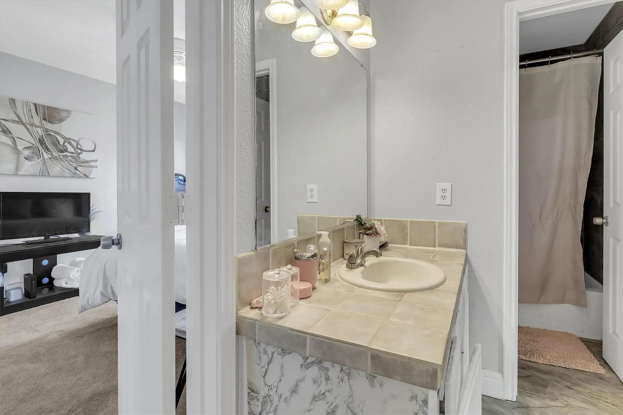 Bathroom vanity with tile countertop, integrated sink, and wall-mounted mirror
