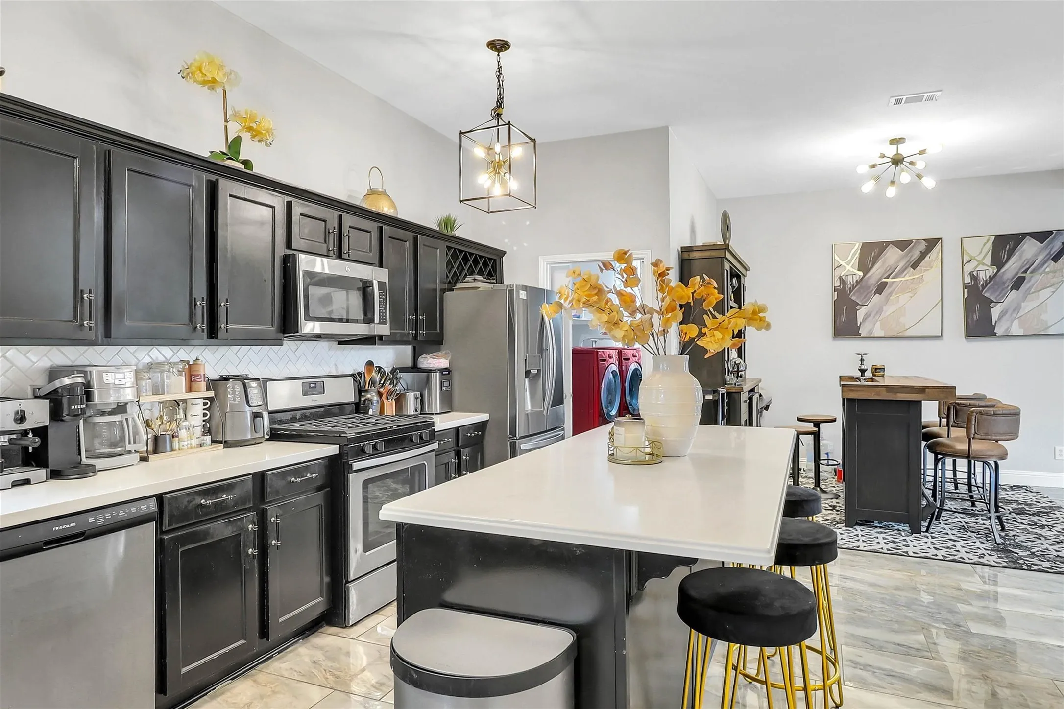 Contemporary kitchen featuring black cabinetry, stainless steel appliances, white countertops, and a white subway tile backsplash