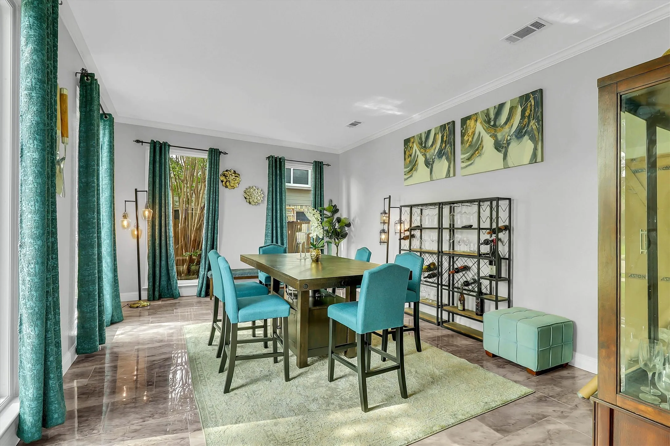 Spacious room featuring polished stone-look flooring, multiple windows, crown molding, and a built-in display cabinet