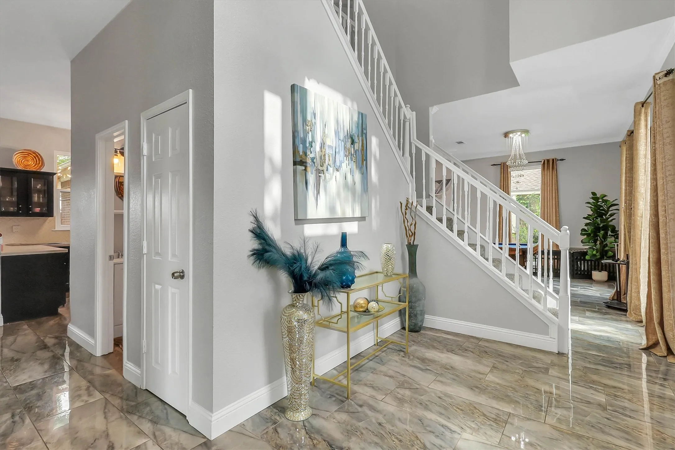 Foyer featuring polished tile flooring, white staircase railing, contemporary wall art, and neutral wall tones