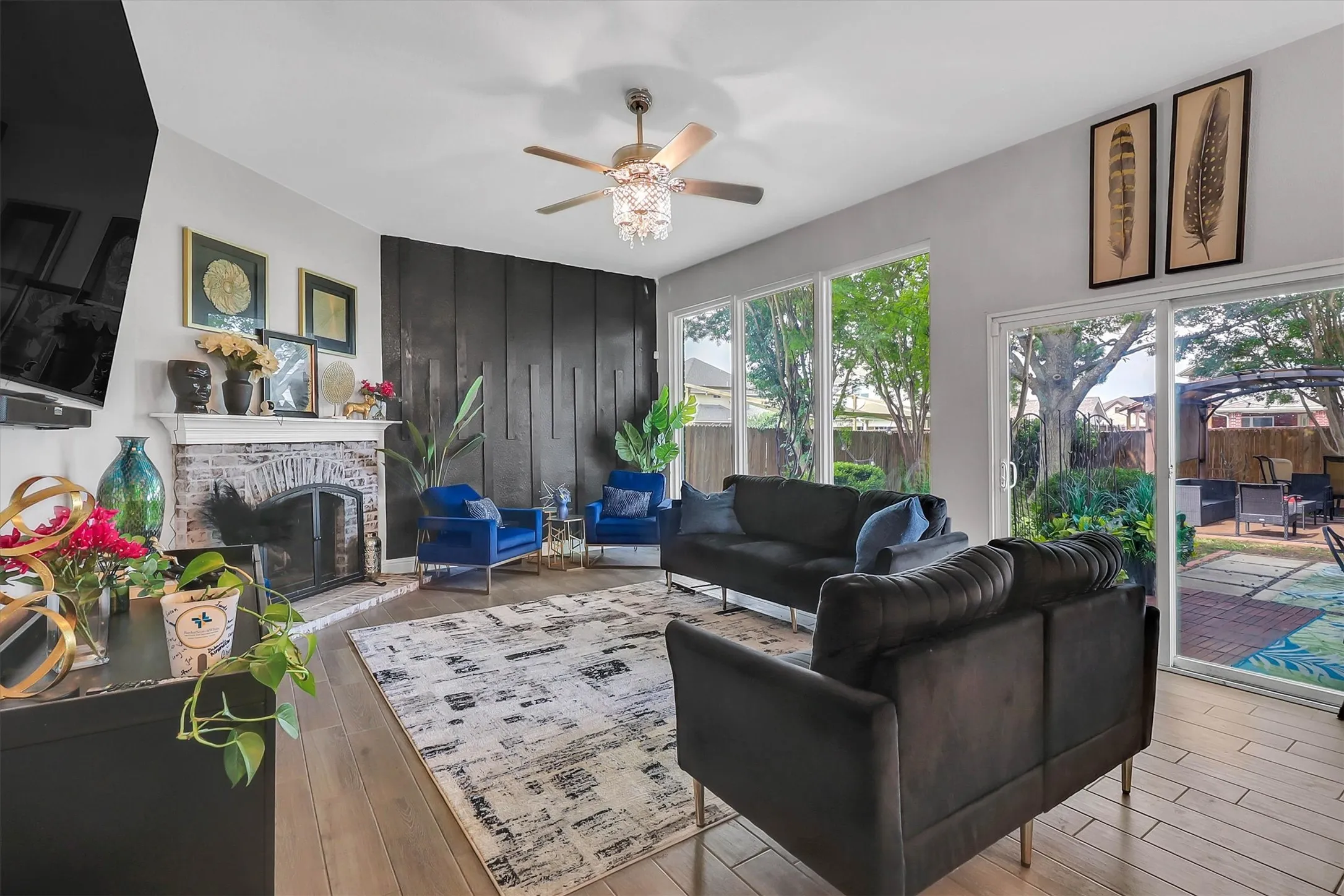 Living area featuring wood-finish flooring, a brick fireplace with mantel, and a dark accent wall