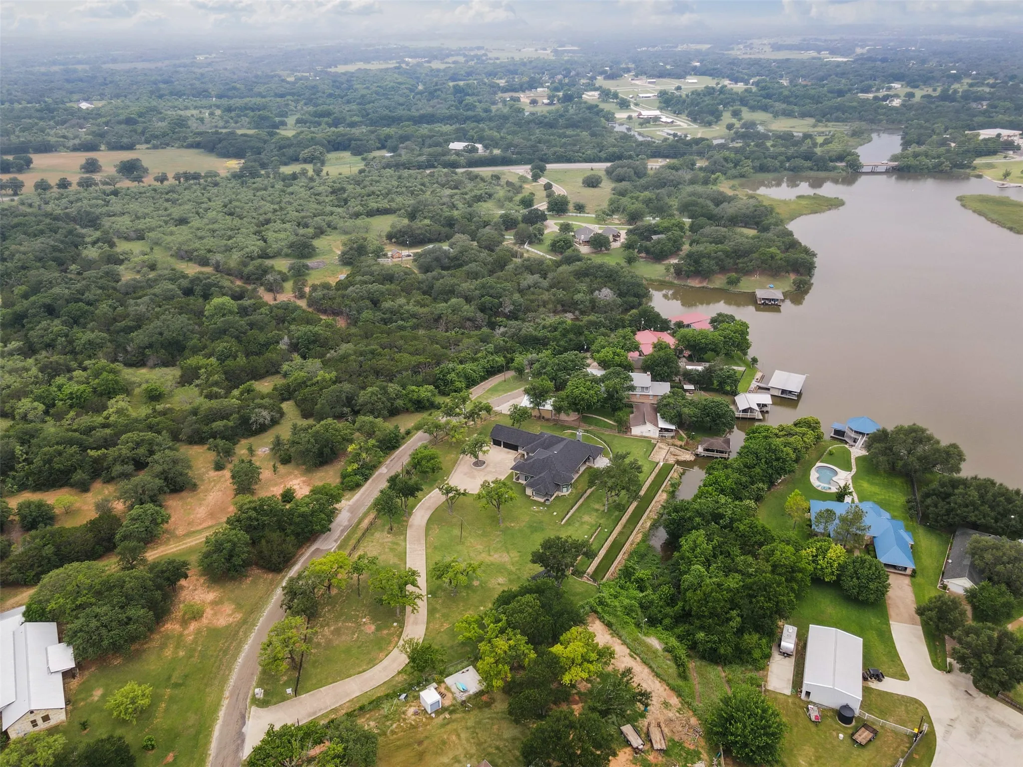 Expansive waterfront property featuring a large residence with a dark roof, private boat slips, and multiple outbuildings