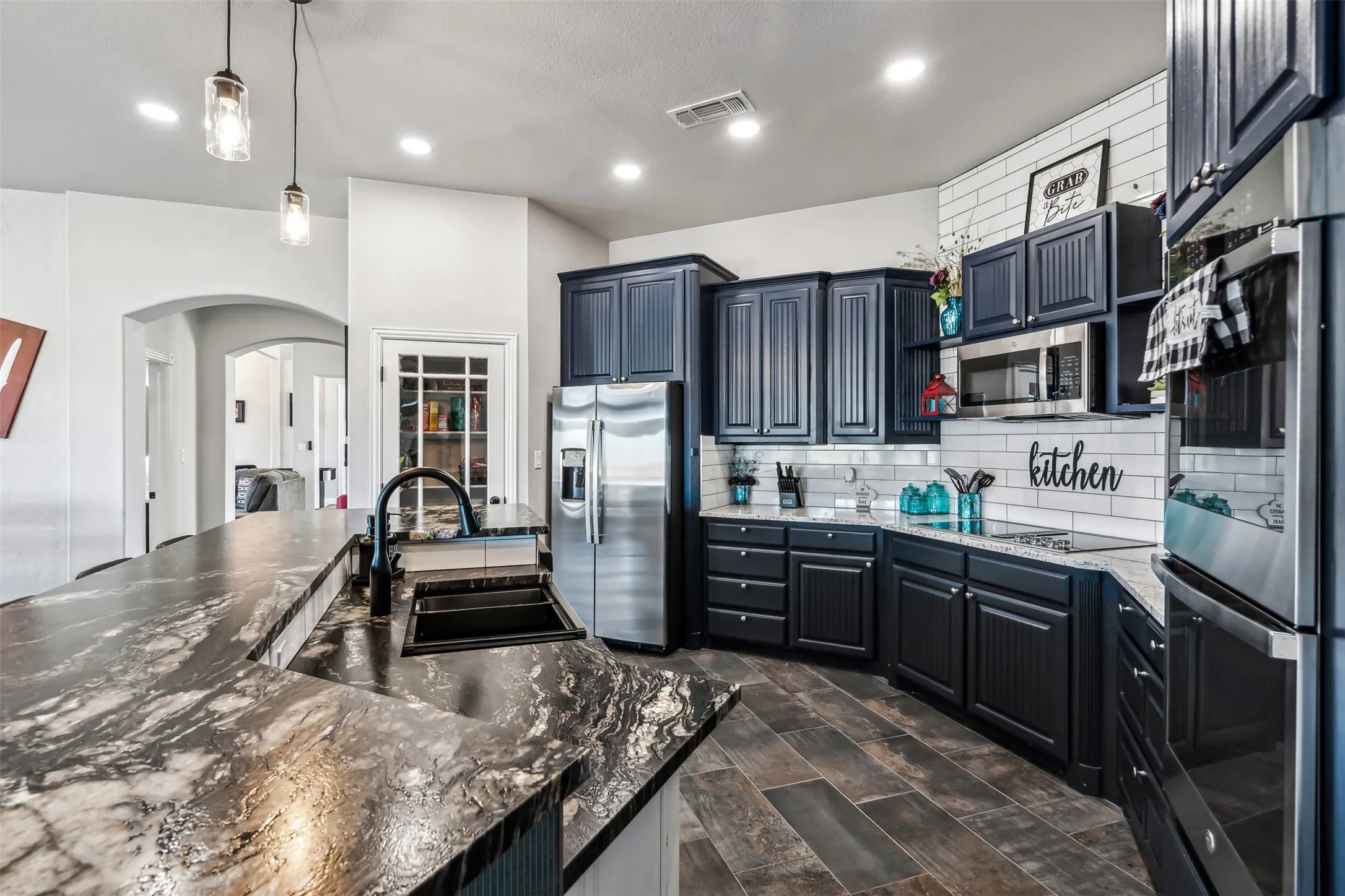 Kitchen featuring dark wood-finish cabinetry, stainless steel appliances, and wood-finish tile flooring