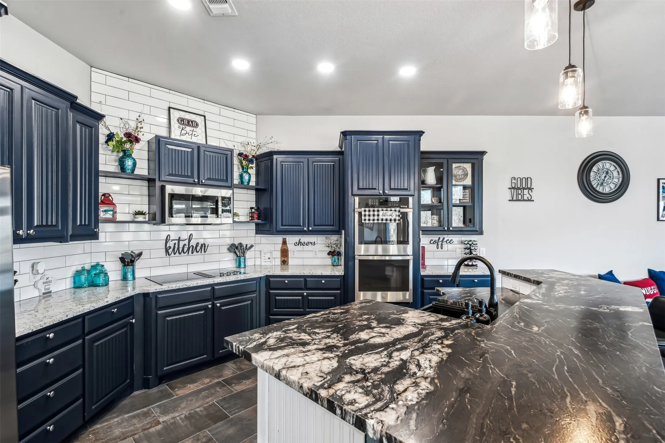 Spacious kitchen featuring dark cabinetry, two-tone countertops, a subway tile backsplash, and built-in stainless steel appliances