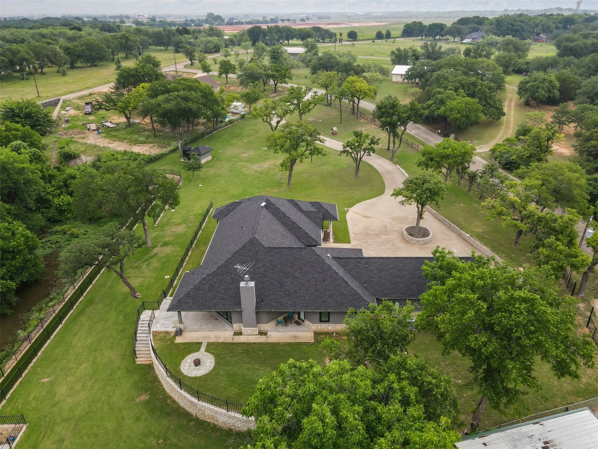 Expansive property featuring a contemporary residence with a dark shingle roof and a prominent chimney