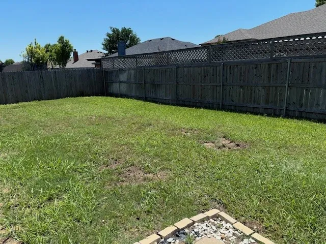 Expansive grass lawn bordered by a wood privacy fence with lattice detailing