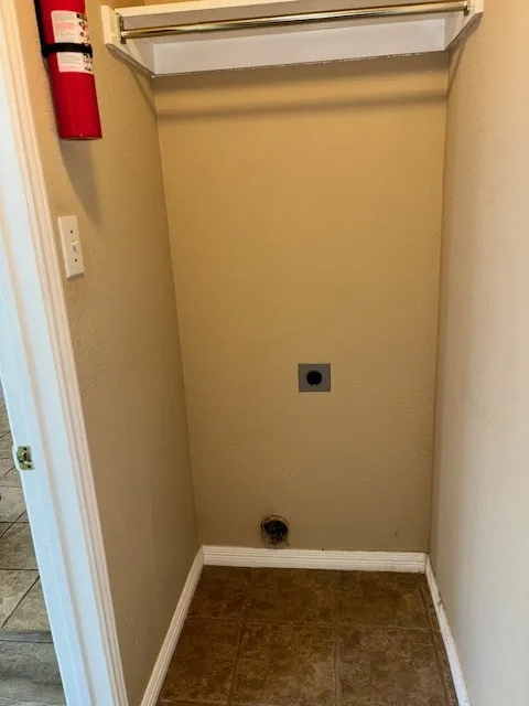 Utility closet featuring a clothing rod, upper shelving, and neutral wall paint