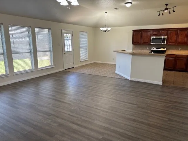 Expansive living area featuring wood-finish flooring, ample natural light from multiple windows, and a ceiling fan