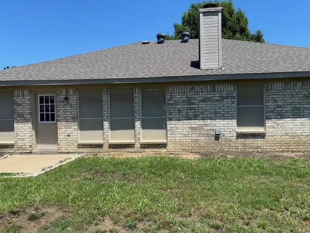 Brick exterior with a gabled roofline, featuring an exterior door with window panes and a wall-mounted light fixture