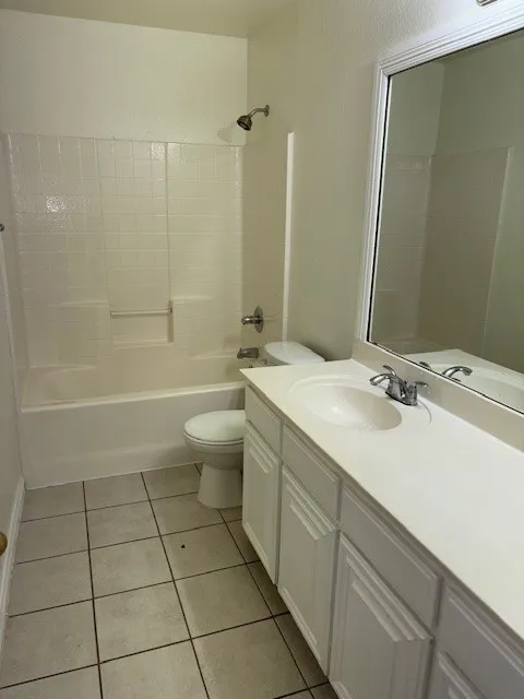 Bathroom featuring a white vanity with integrated sink, chrome faucet, and a wall-mounted mirror
