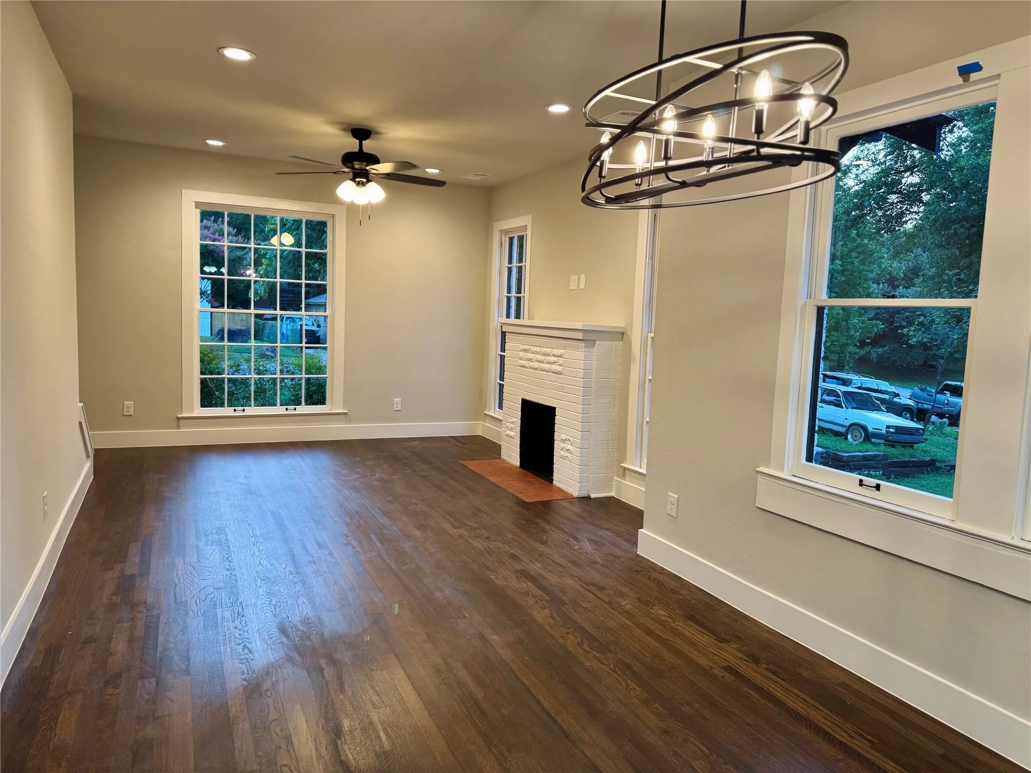 Unfurnished living room featuring a chandelier, recessed lighting, dark wood finished floors, a ceiling fan, and healthy amount of natural light