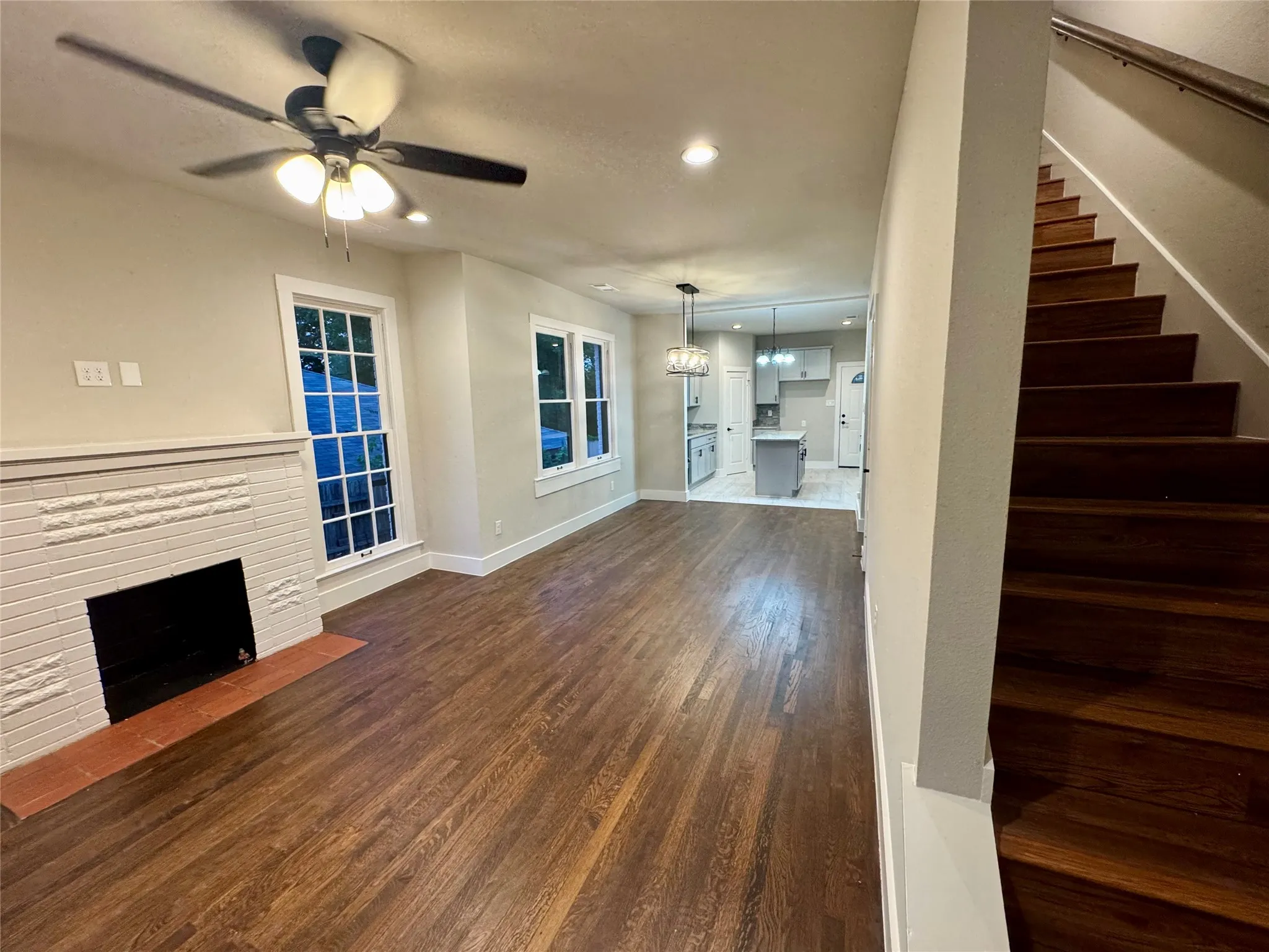 Unfurnished living room with a ceiling fan, stairs, dark wood finished floors, a fireplace, and recessed lighting