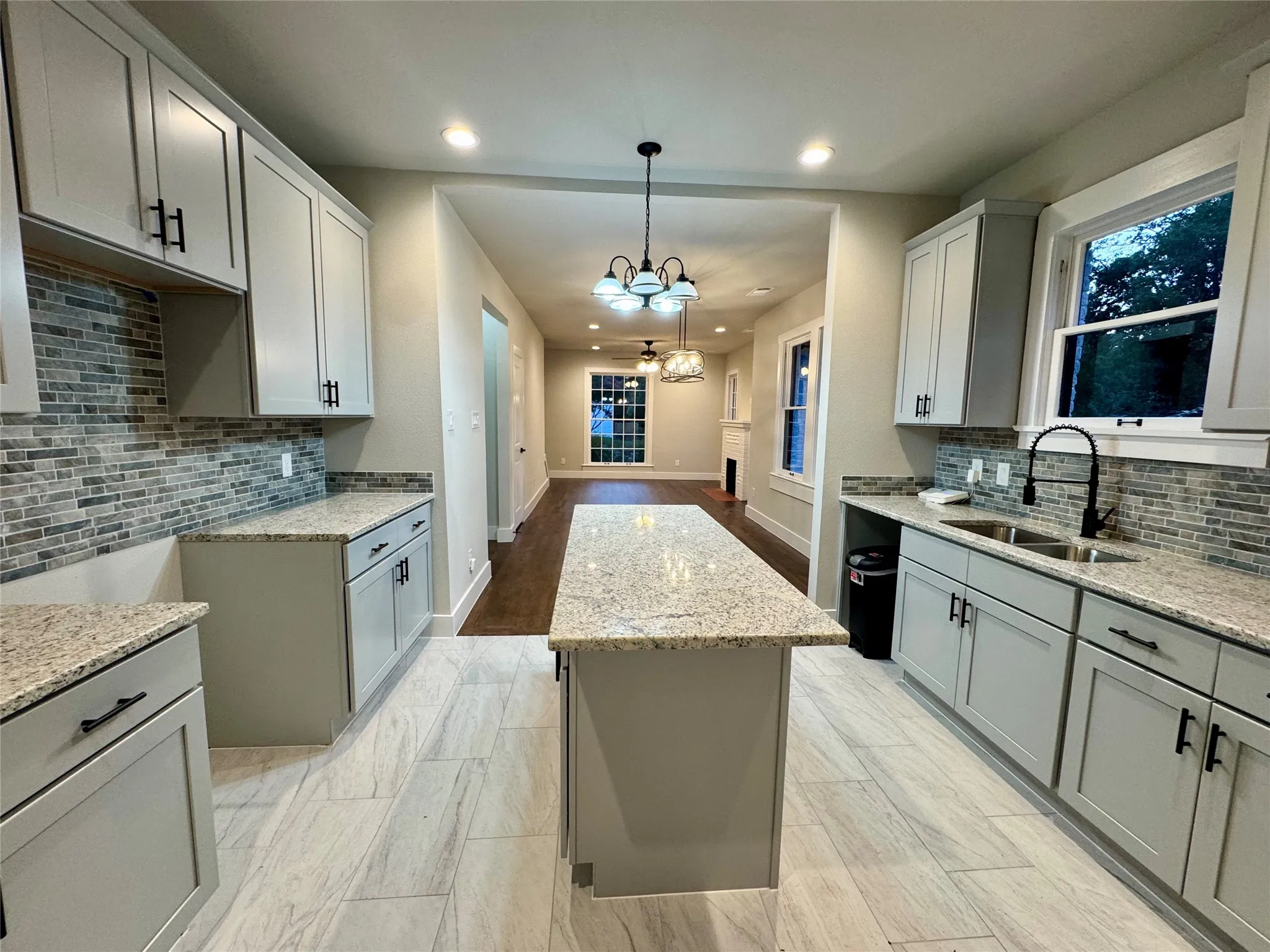 Kitchen featuring a kitchen island, a chandelier, light stone counters, backsplash, and recessed lighting