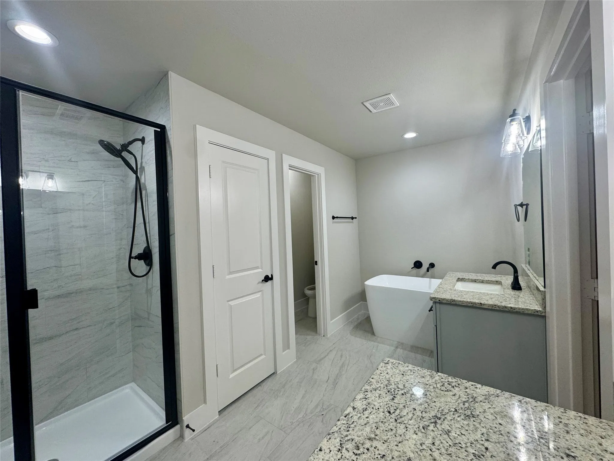 Bathroom featuring vanity, a shower stall, a freestanding tub, recessed lighting, and marble finish floors