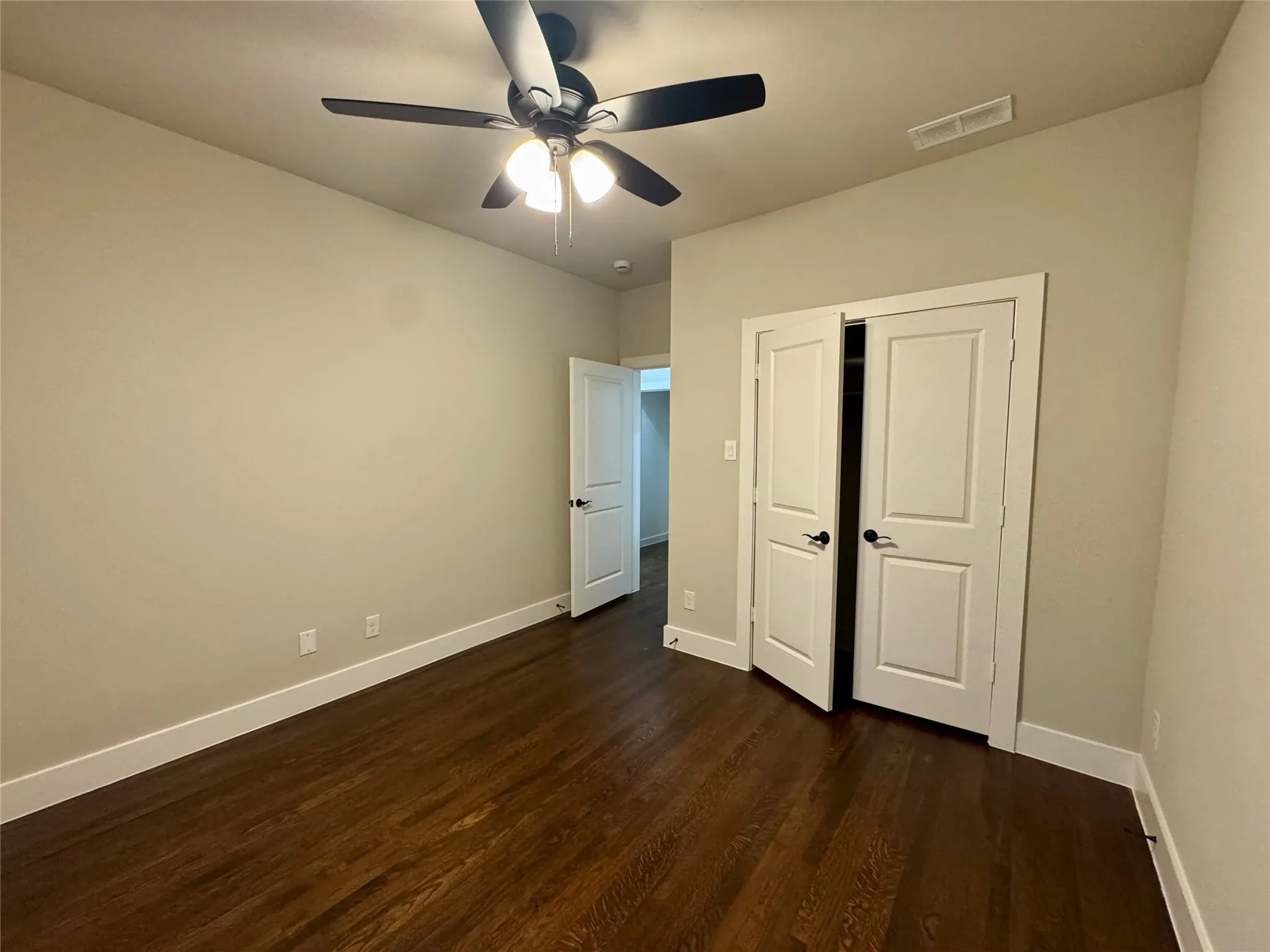 Unfurnished bedroom featuring dark wood finished floors, a closet, and a ceiling fan