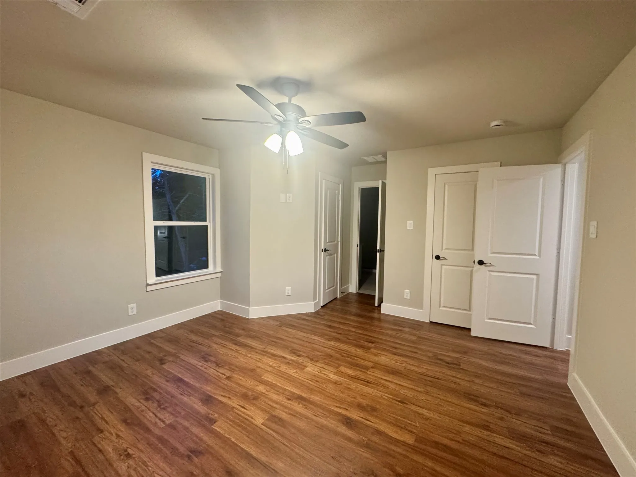 Unfurnished bedroom featuring dark wood-type flooring and ceiling fan